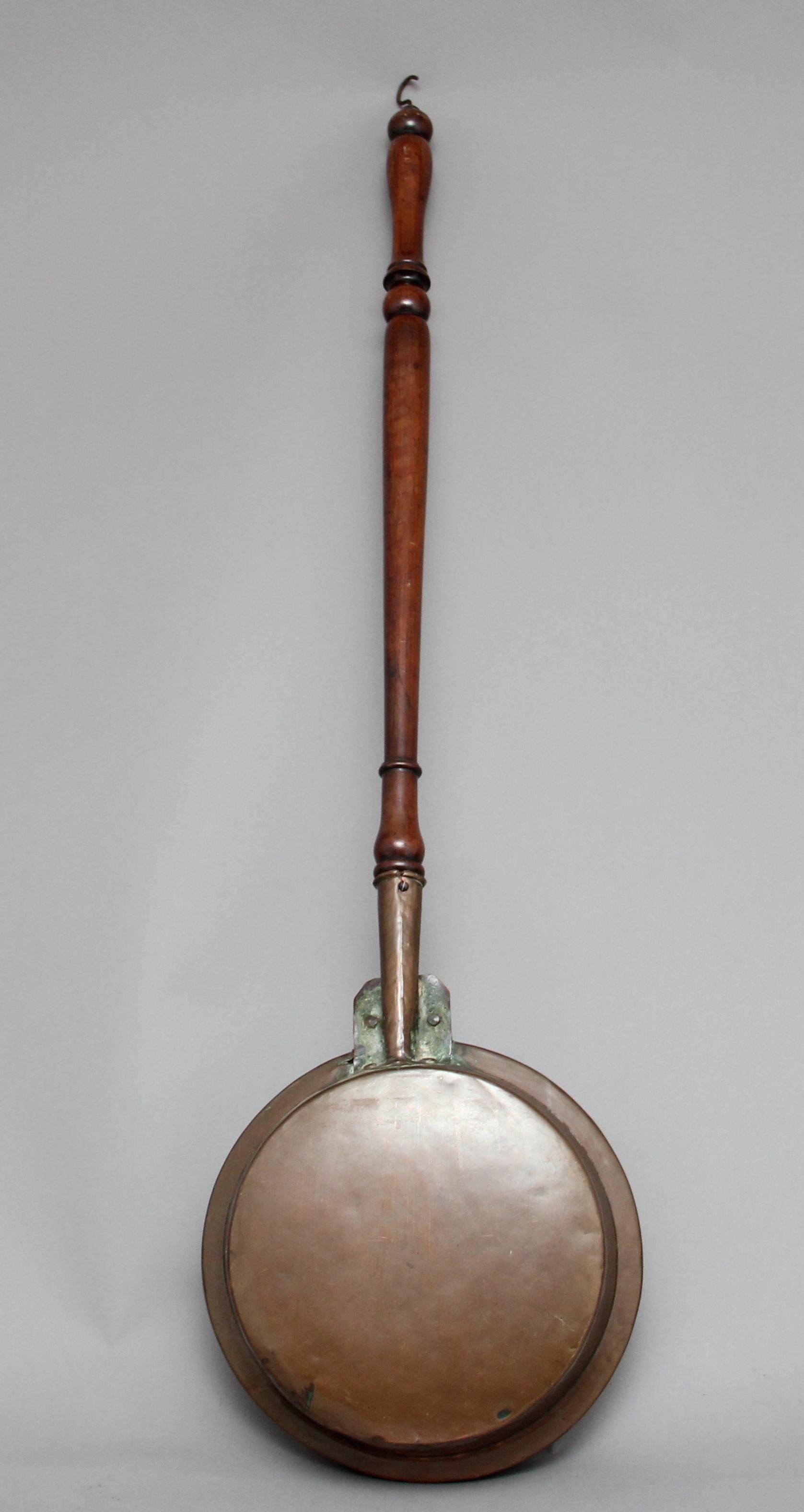 19th century copper bed warming pan with pierced and engraved decoration and a turned mahogany handle with brass hook, circa 1860.
 