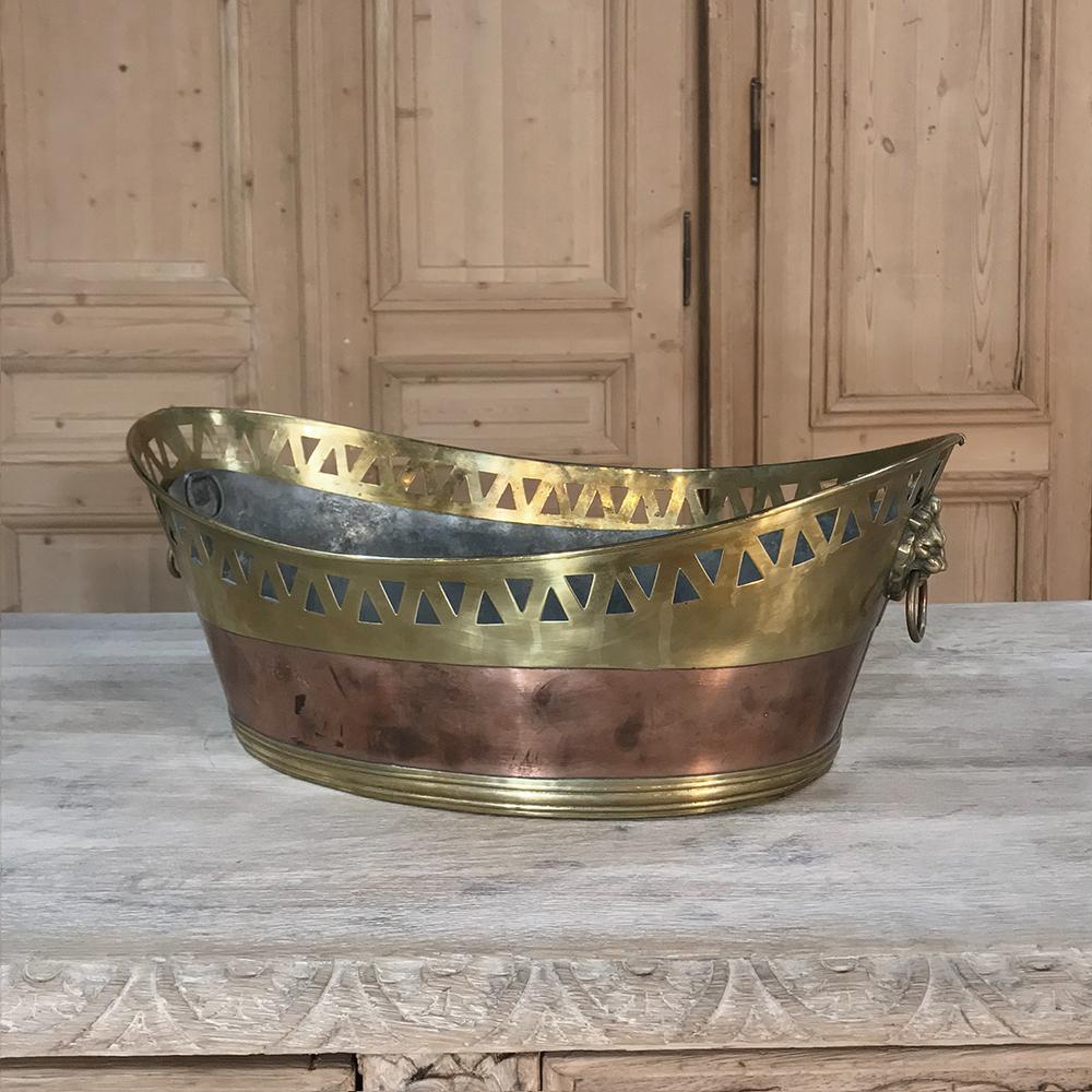 19th Century copper & brass Jardiniere features a unique boat-shaped form with pierced gallery rail all around the top rim. The rail and base are in brass, with copper in between. Cast bronze lions' heads with ring pulls appear on the ends to use as