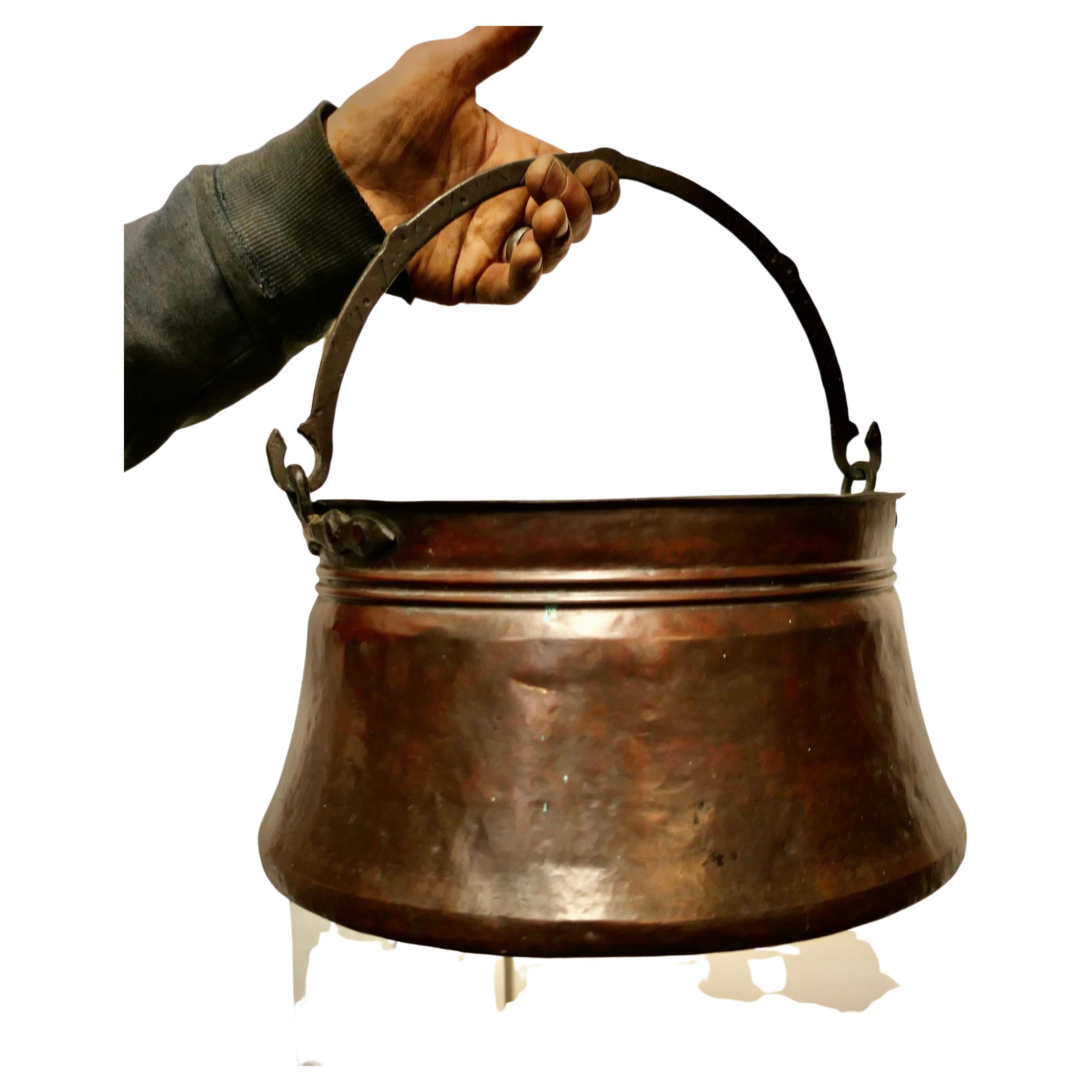 19th century copper cooking pot, Cauldron 

This is a lovely early cooking pot, it has been made in hand beaten copper The pot is wider at the base and has a rolled top, the Iron handle swings through 180 degrees and has a very primitive engraved