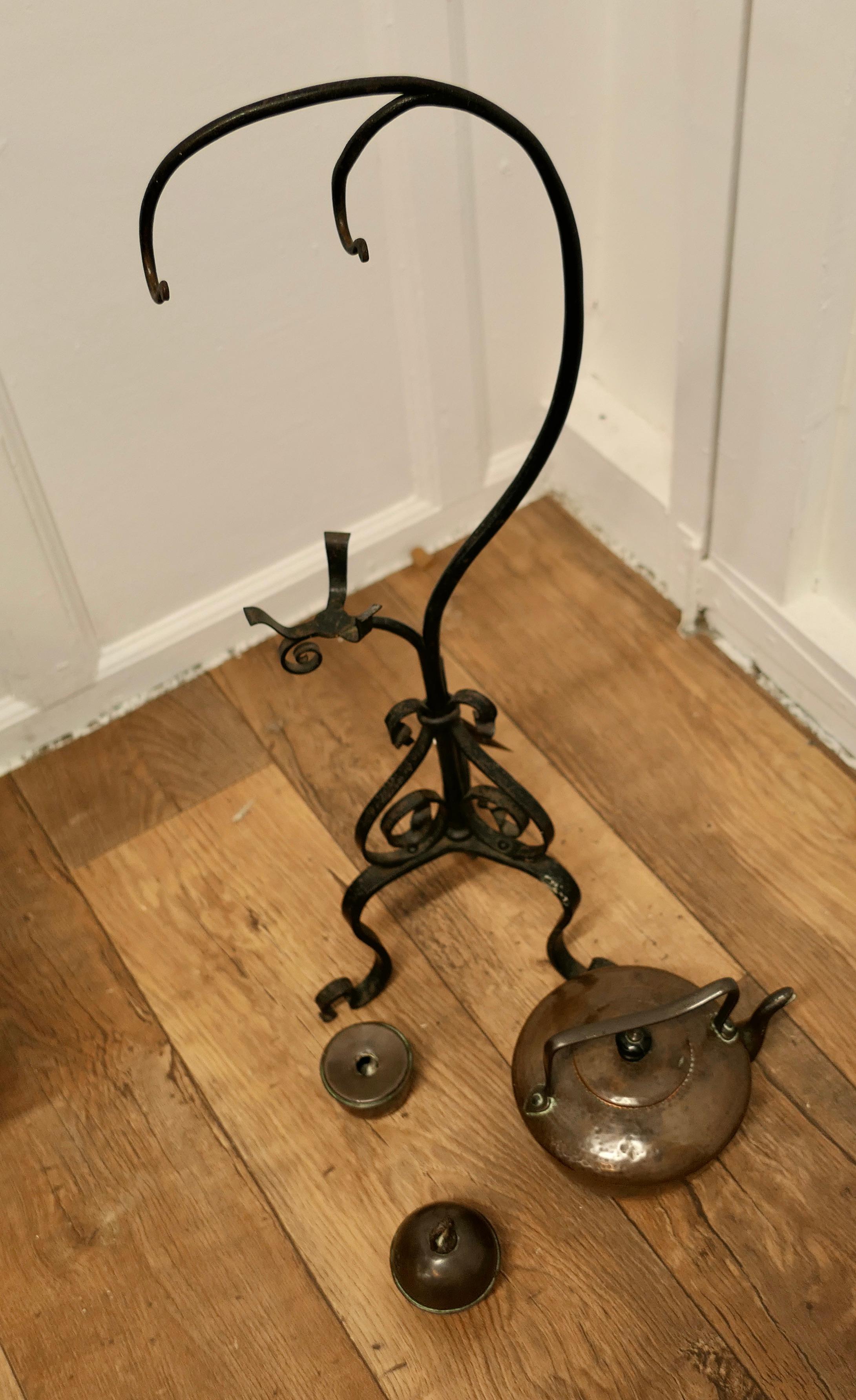 19th century Copper Swinging Sprit Kettle on a Wrought Iron stand 

This charming Arts and Crafts spirit Kettle hangs from a wrought iron stand, it has a copper spirit burner which hangs just below and a copper ball weight which is filled with