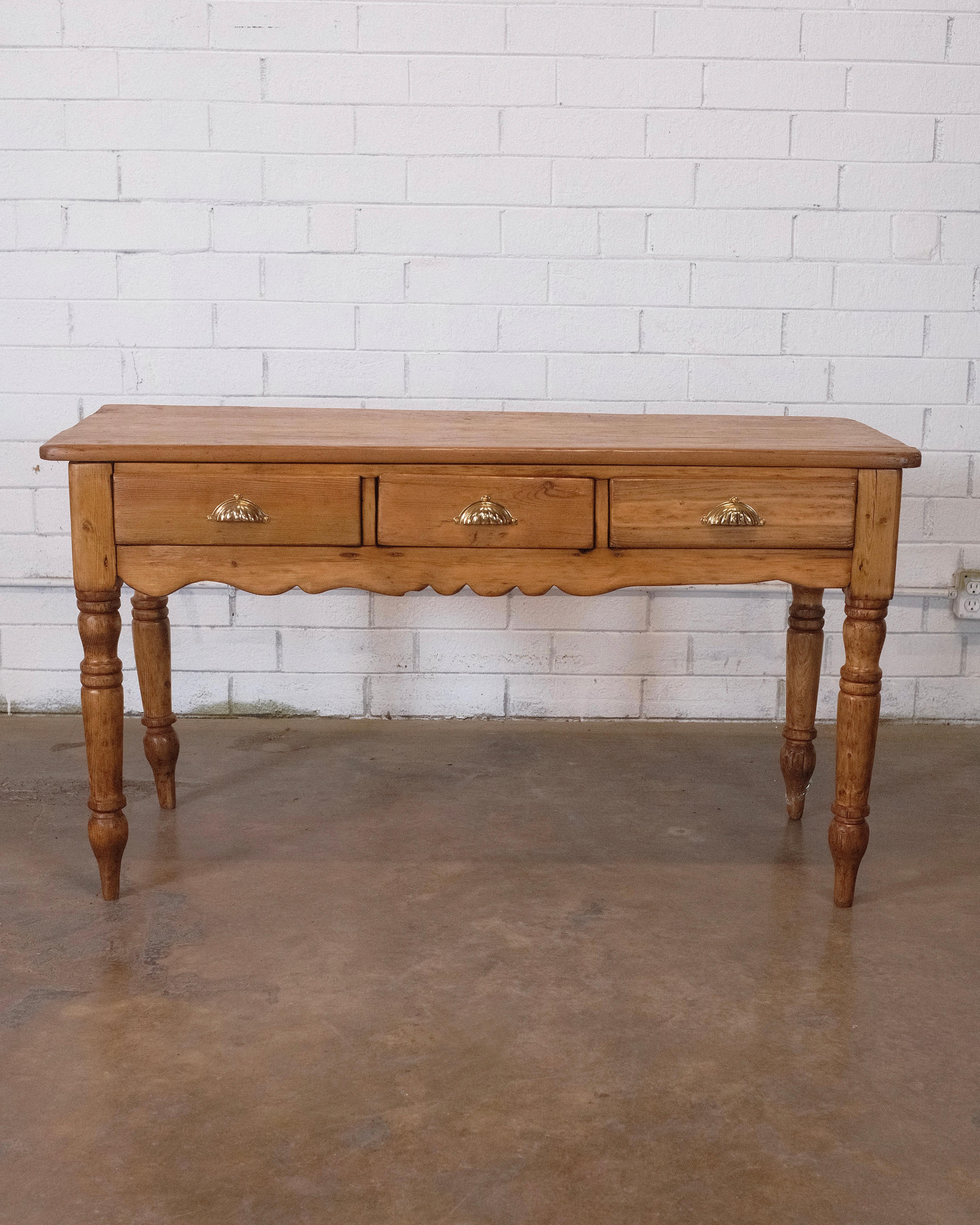 This charming 19th-century country English provincial farmhouse work table, console, or sideboard is a delightful piece crafted from pine. Its warm and rustic aesthetic embodies the character of a bygone era, making it a versatile addition to any