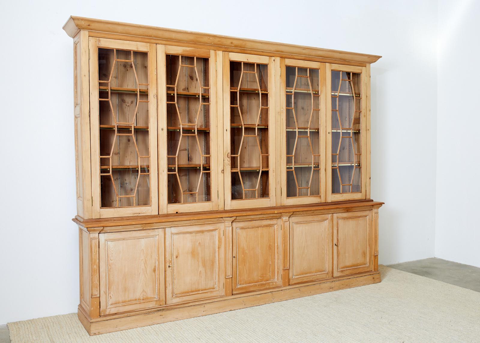 Grand 20th century country English library bookcase cabinet beautifully constructed from pine. Features a two-part case the top having five classic astragal glazed doors with lock hardware and keys. Inside are three adjustable height shelves with a