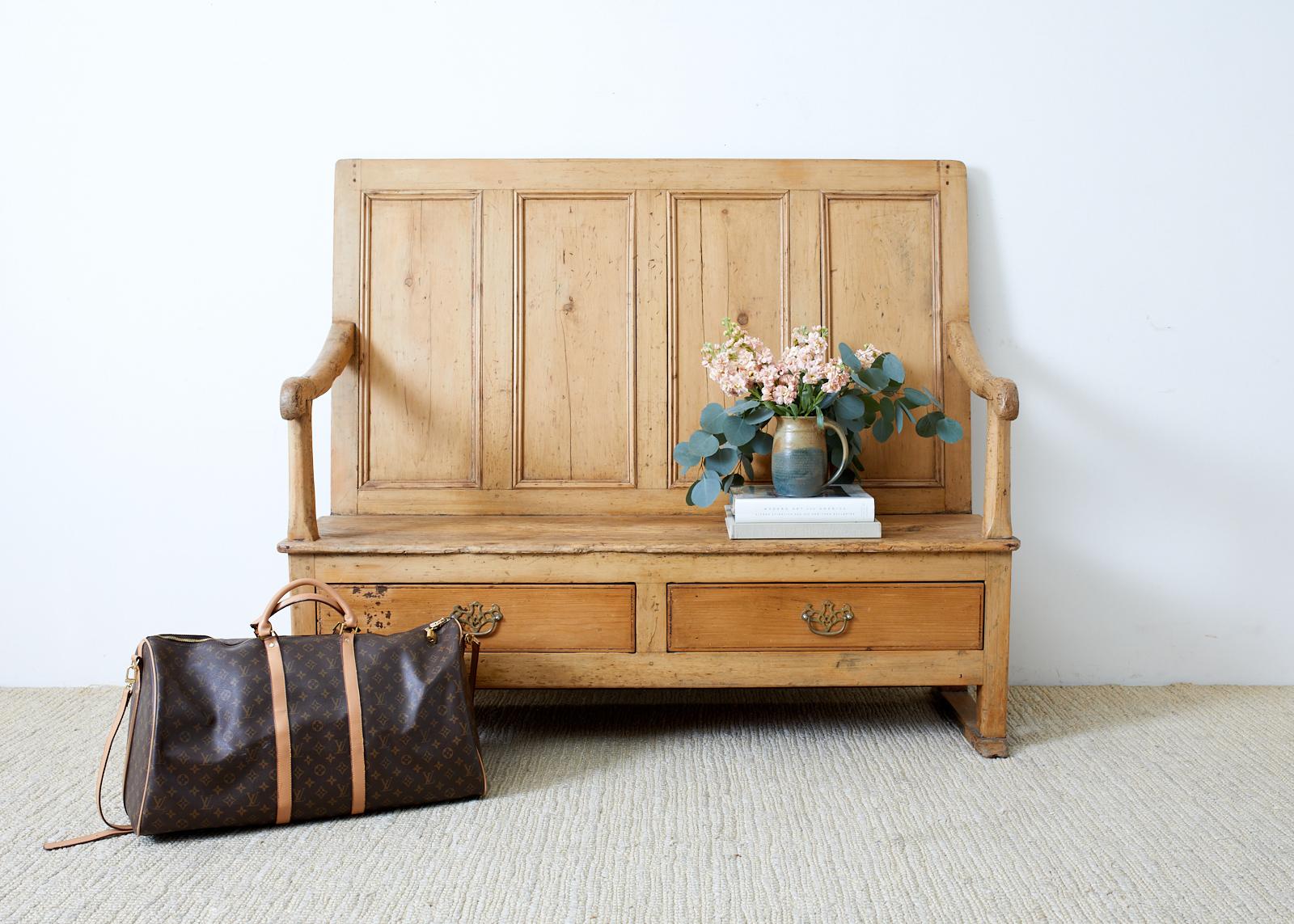 Rustic early 19th century country English hall settle or bench. Constructed from pine with mortise and tenon joinery and wood peg joinery. The thick pine has a beautifully aged patina and soft feel. The straight back is decorated with panels.