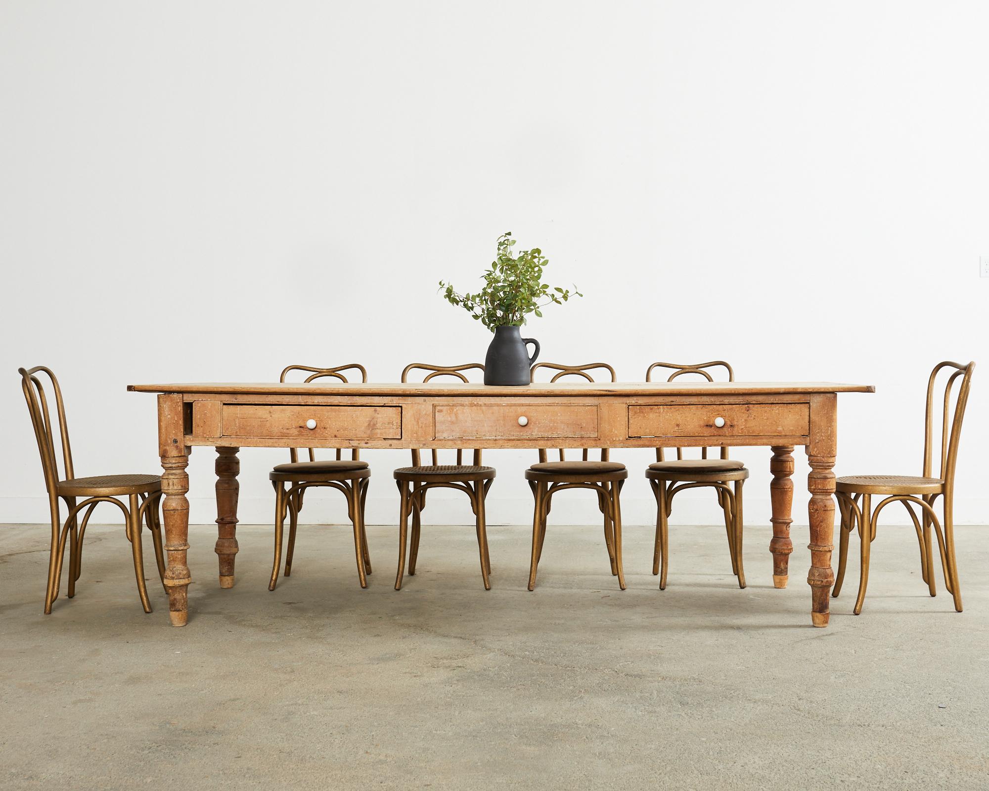 Gorgeous 19th century country English provincial style farmhouse dining table featuring a scrubbed, weathered patina. The plank top measures nearly 100 inches long with breadboard ends. The apron is fitted with two working storage drawers centered