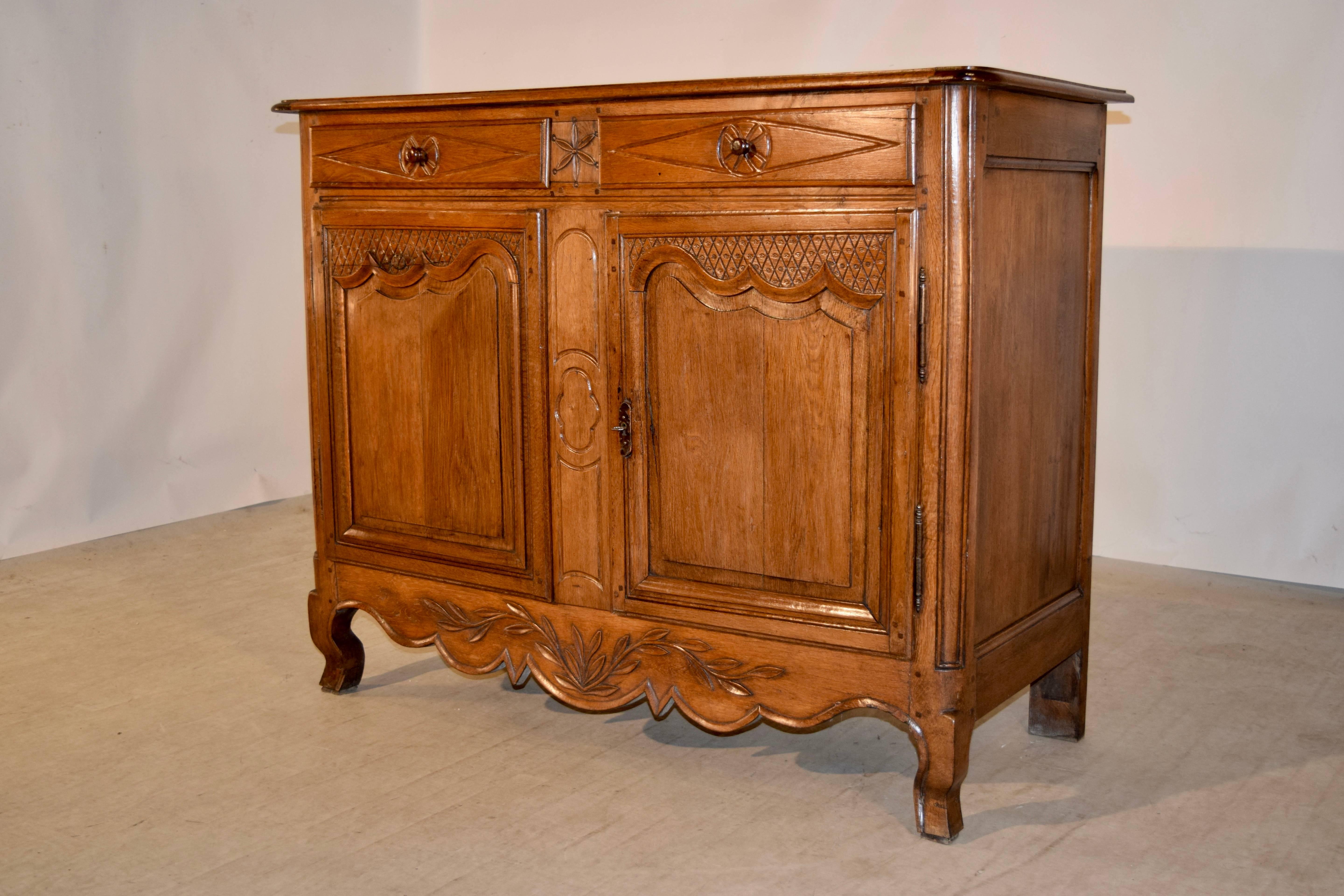 19th century French buffet made from oak. The top is made of three planks and is banded on the ends to keep shrinkage at bay. There is a beveled edge and rounded corners as well. The sides are paneled and the front contains two drawers which have