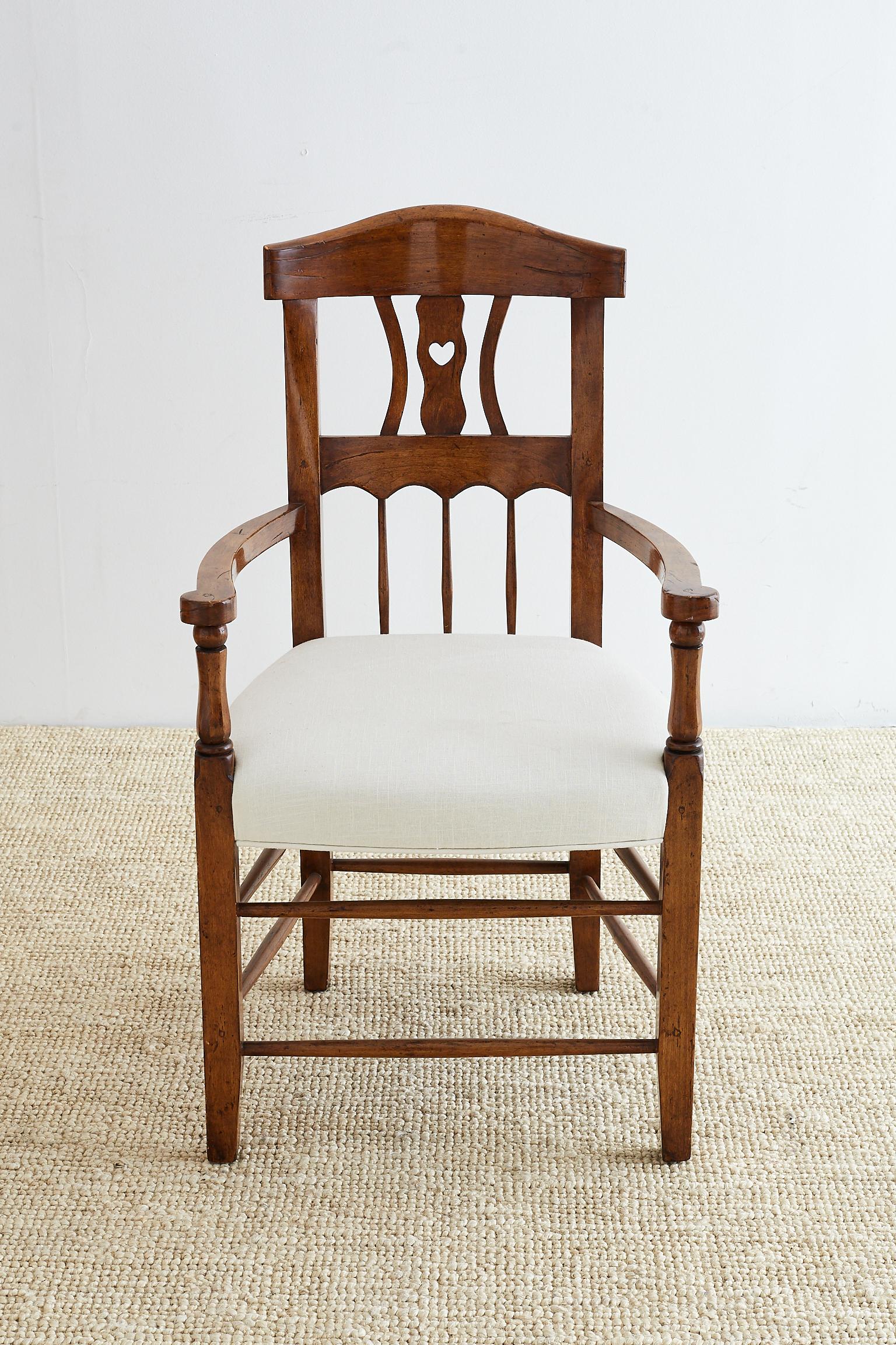 19th century French country armchair carved from fruitwood. Features a curved back with a whimsical carved heart backsplat. Constructed with wood peg joinery and newly upholstered in white linen. Recently renovated and finished in a rich dark stain.