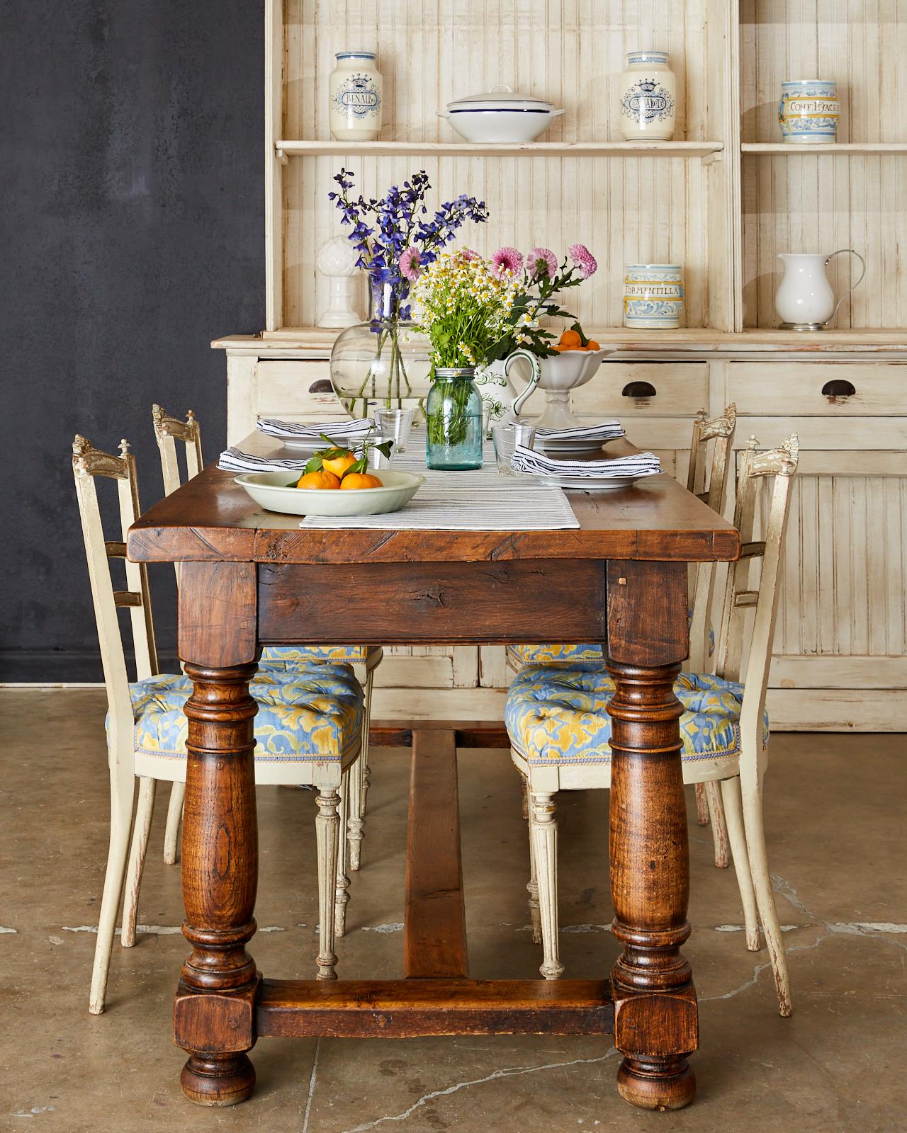 Rustic 19th century country French farmhouse dining table crafted from chestnut. Made in the Provincial style having a thick, nearly 2 inch plank top showcasing the rich chestnut grain patterns and knots. The trestle style base has a drawer in the