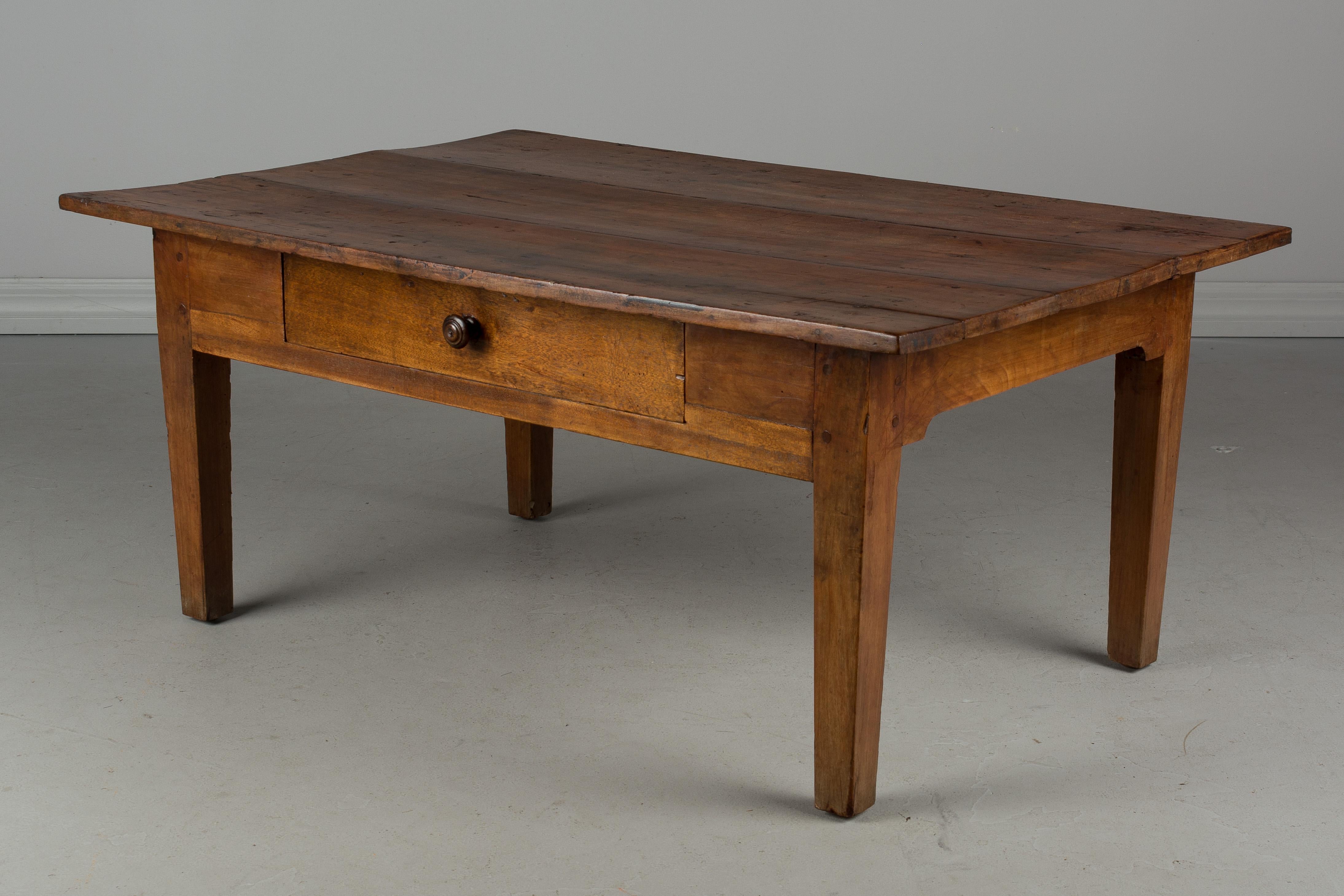 A 19th century Country French coffee table made of cheerywood. Dovetailed drawer. Pegged construction. Waxed patina. Used to be a small kitchen table and the legs were shorten.