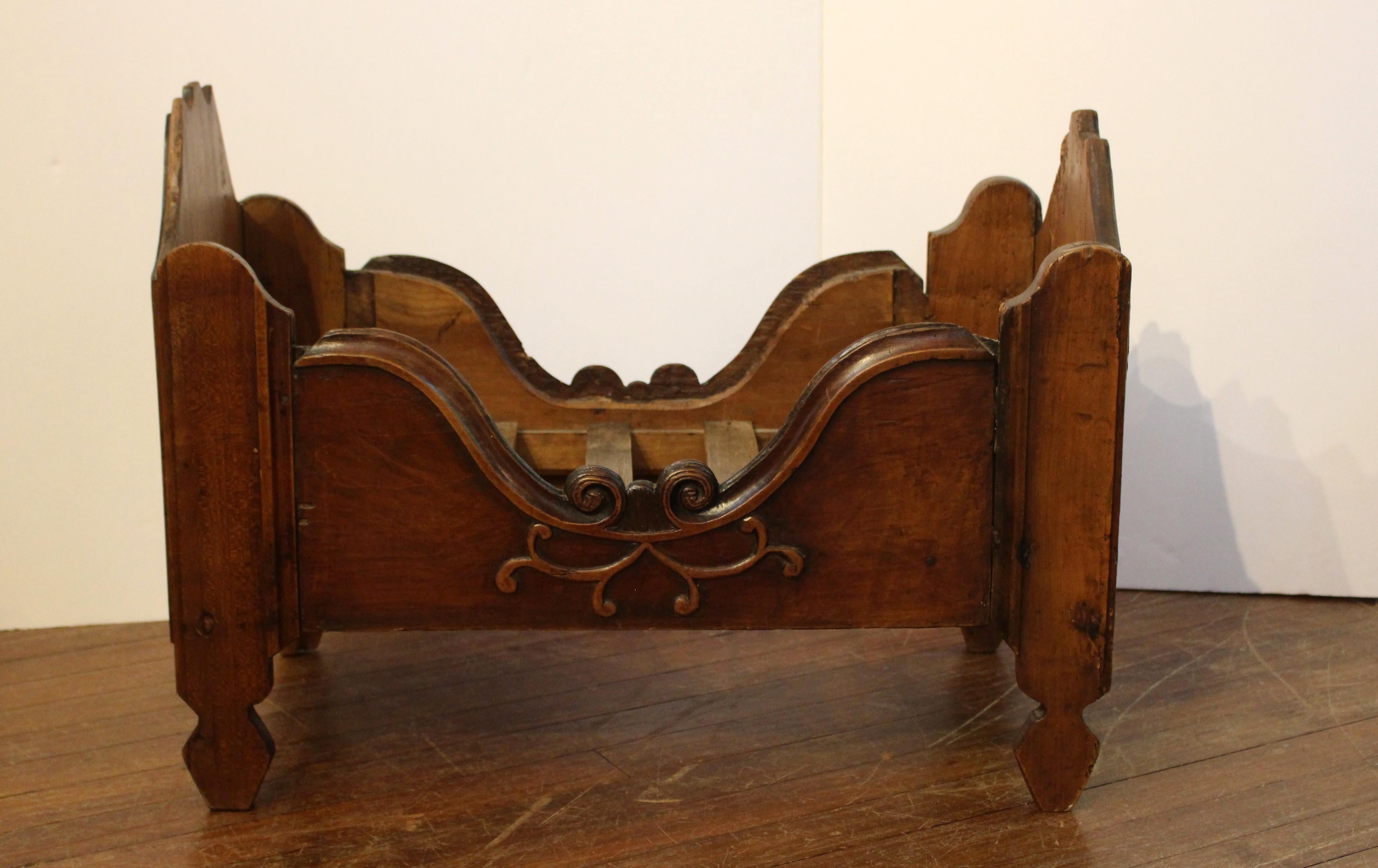 Late 19th-early 19th century country French Directoire period infant's bed. Ideal for a doll collection or beloved mini-canine or cat. Fruitwood. Nicely molded throughout. The sides with tendril carving and extensive whorl design decoration. The