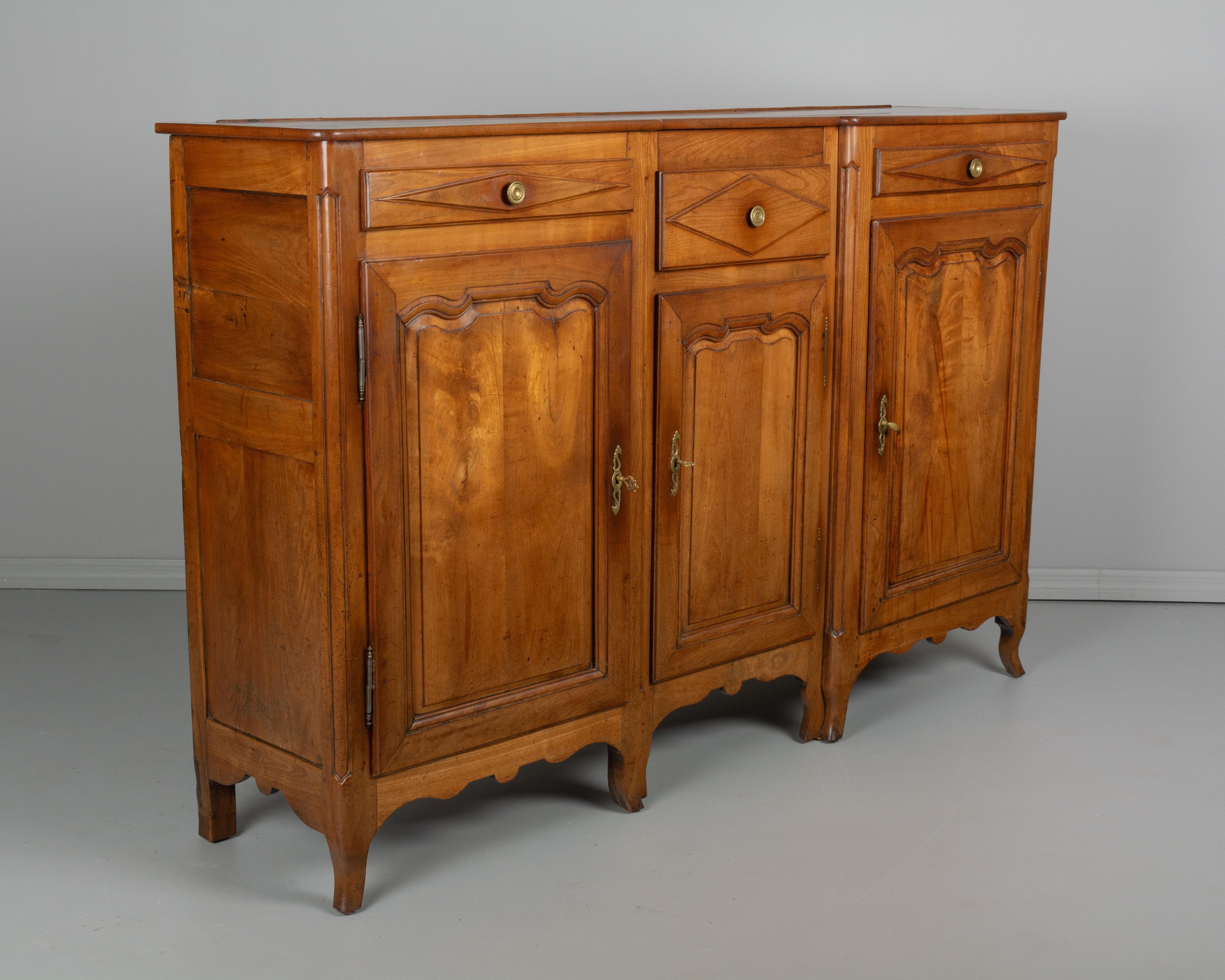 An 19th century Country French enfilade, or sideboard from Picardie (Northern France) made of solid cherry wood. Simple hand-carved details and raised panel doors. Three doors open to five interior shelves providing ample storage. Three drawers with