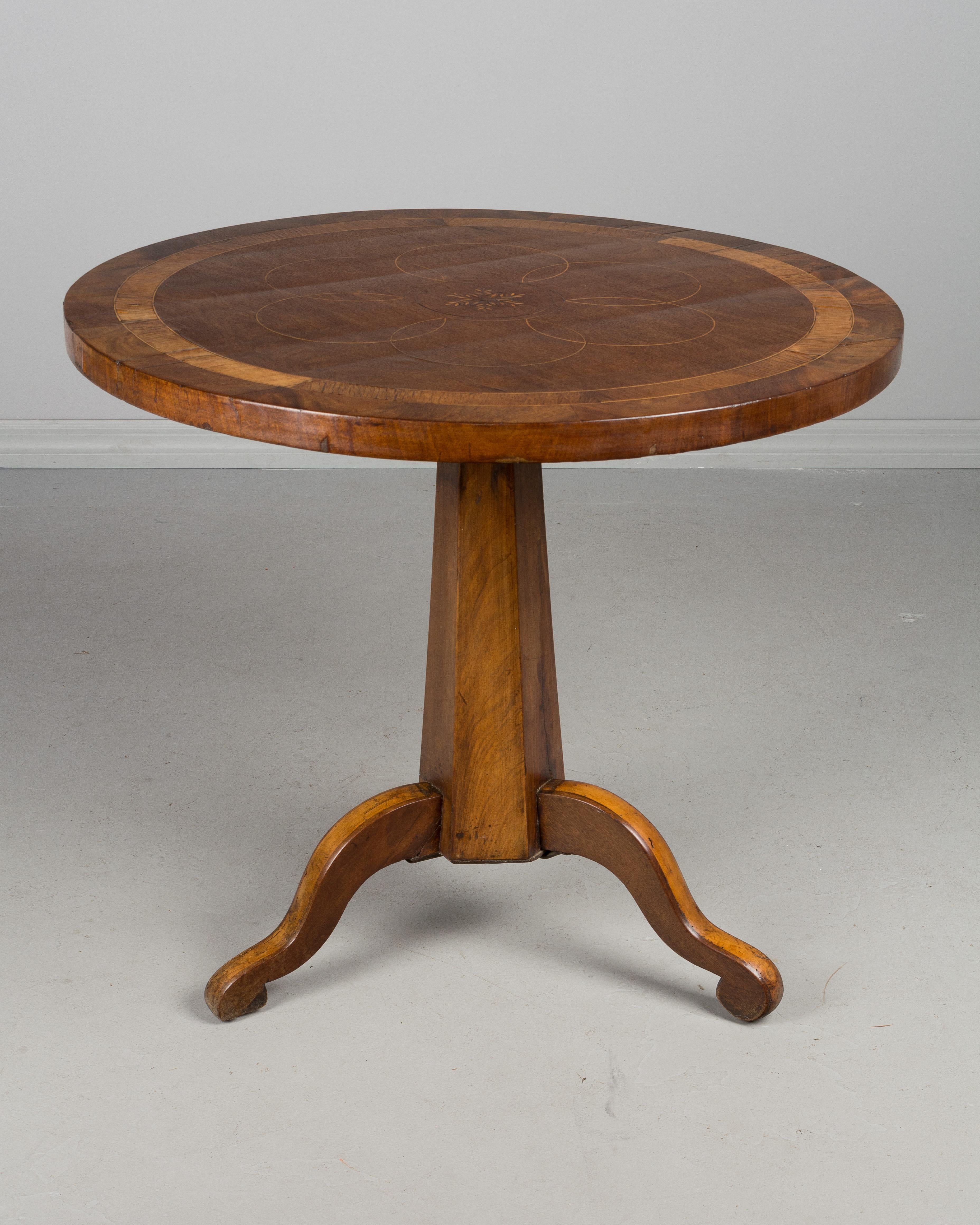 A 19th century Country French gueridon, or circular side table with a marquetry top of inlaid walnut veneer and a solid walnut base with tripod legs. The legs were reinforced with iron on the underside at a later date and the table is sturdy.