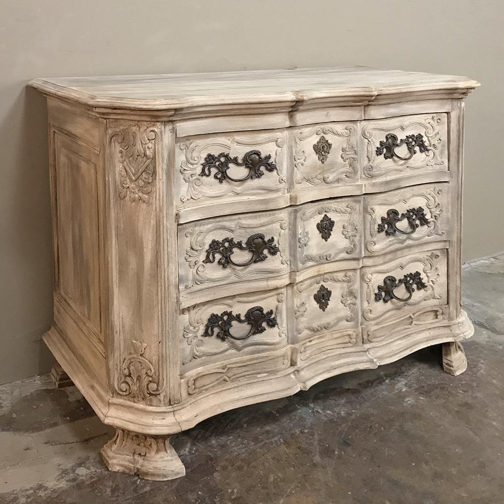 19th century Country French Louis XIV stripped commode features a timeless arbalette facade adorned with hand-carved molding, foliates, and enriched with exquisitely cast bronze pulls and keyguards. The arbalette form refers to the shape of an
