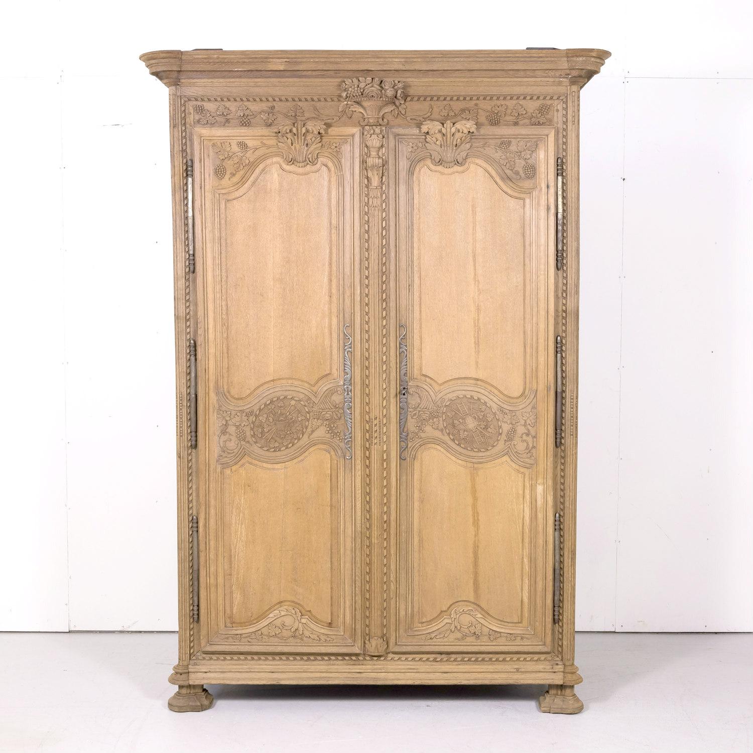 Early 19th century country French Louis XIV style bleached armoire de marriage or wedding armoire, circa 1810s. Handcrafted of old growth French oak in the Normandy region, this intricately carved wedding or marriage armoire features symbolic