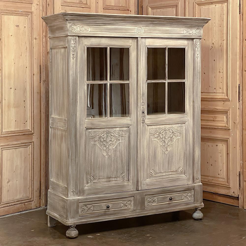 19th Century country French Louis XIV white washed bookcase is the perfect choice for storage, display and adding a timeless panache to your decor! Hand-crafted from solid oak, it features a boldly molded crown with stylized carvings of shell,