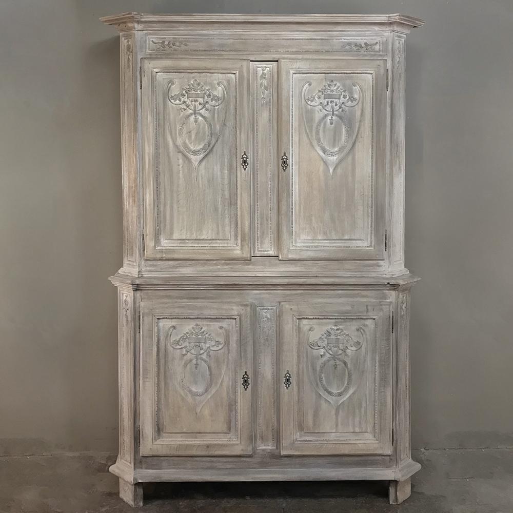 19th century country French Louis XVI stripped buffet a deux corps is ideal for any room that needs extra storage, with four cabinets with capacious interiors enclosed by exquisitely sculpted bas relief in the neoclassical style from the crown to