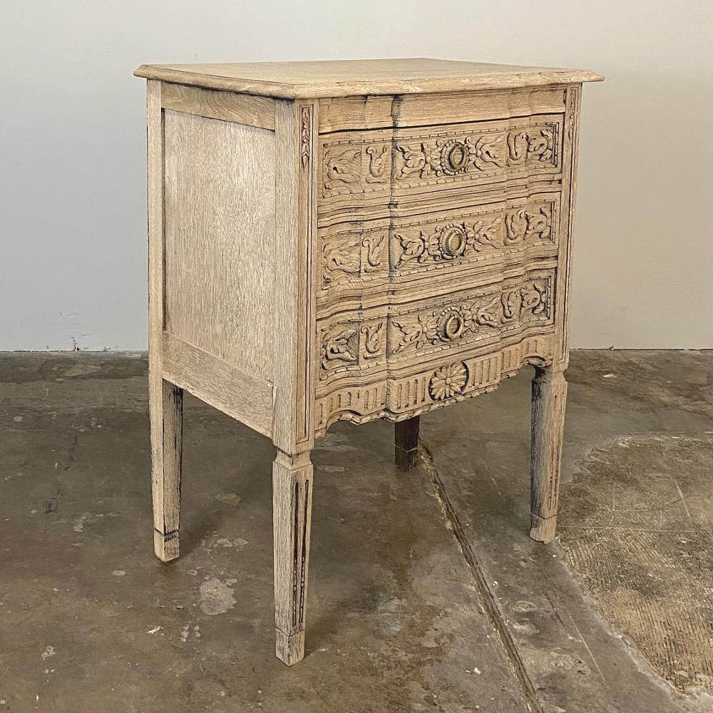 19th century Country French Louis XVI stripped commode was lovingly handcrafted and carved from solid old-growth oak, and features tailored neoclassical architecture melded with timeless foliate motifs across the entire facade. Exceptional molded