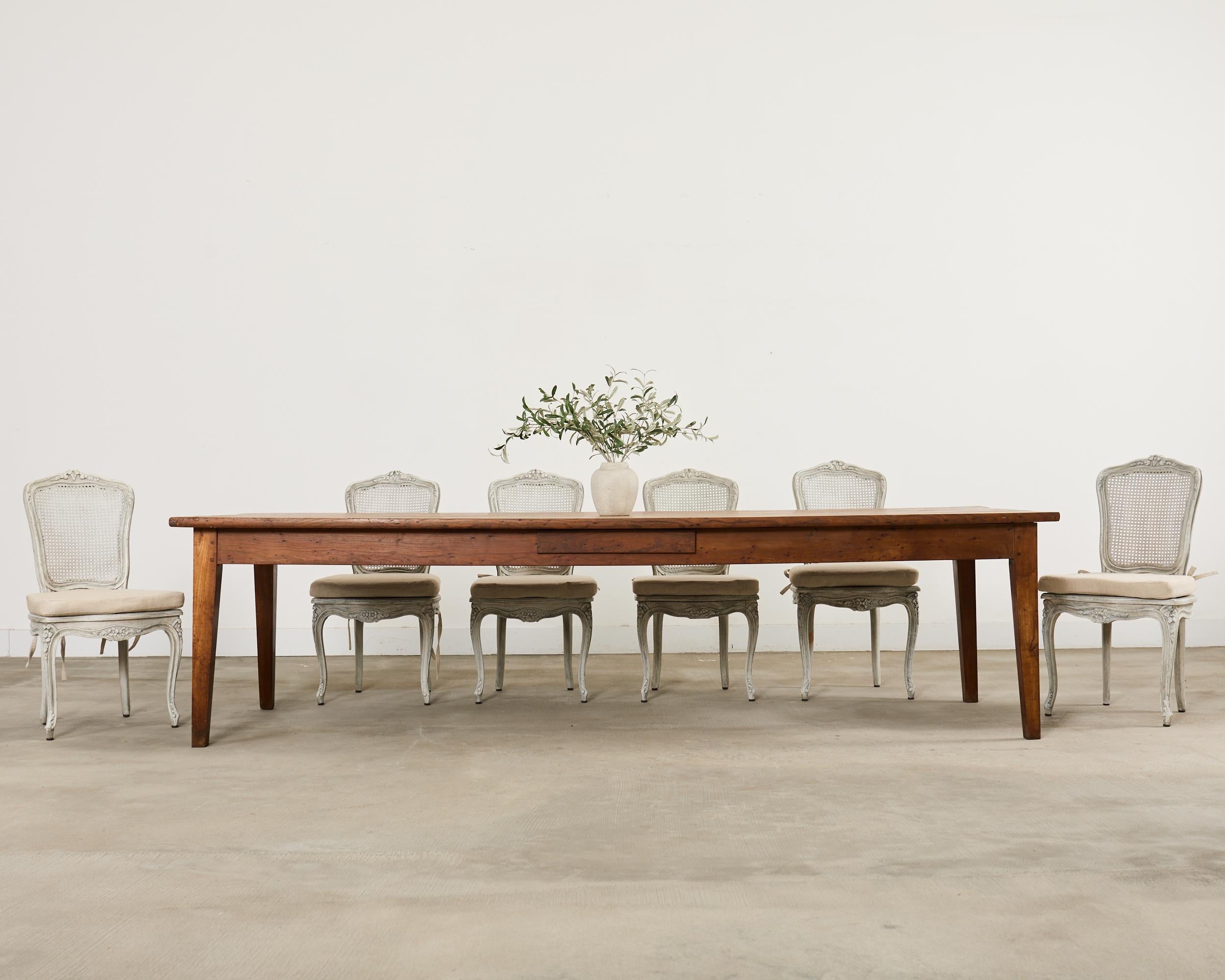 Quintessential 19th century country French provincial style farmhouse table made on a grand scale measuring nearly 10 feet long. Hand-crafted from oak the table features a thick plank top with a beautifully weathered patina on the oak finish. The