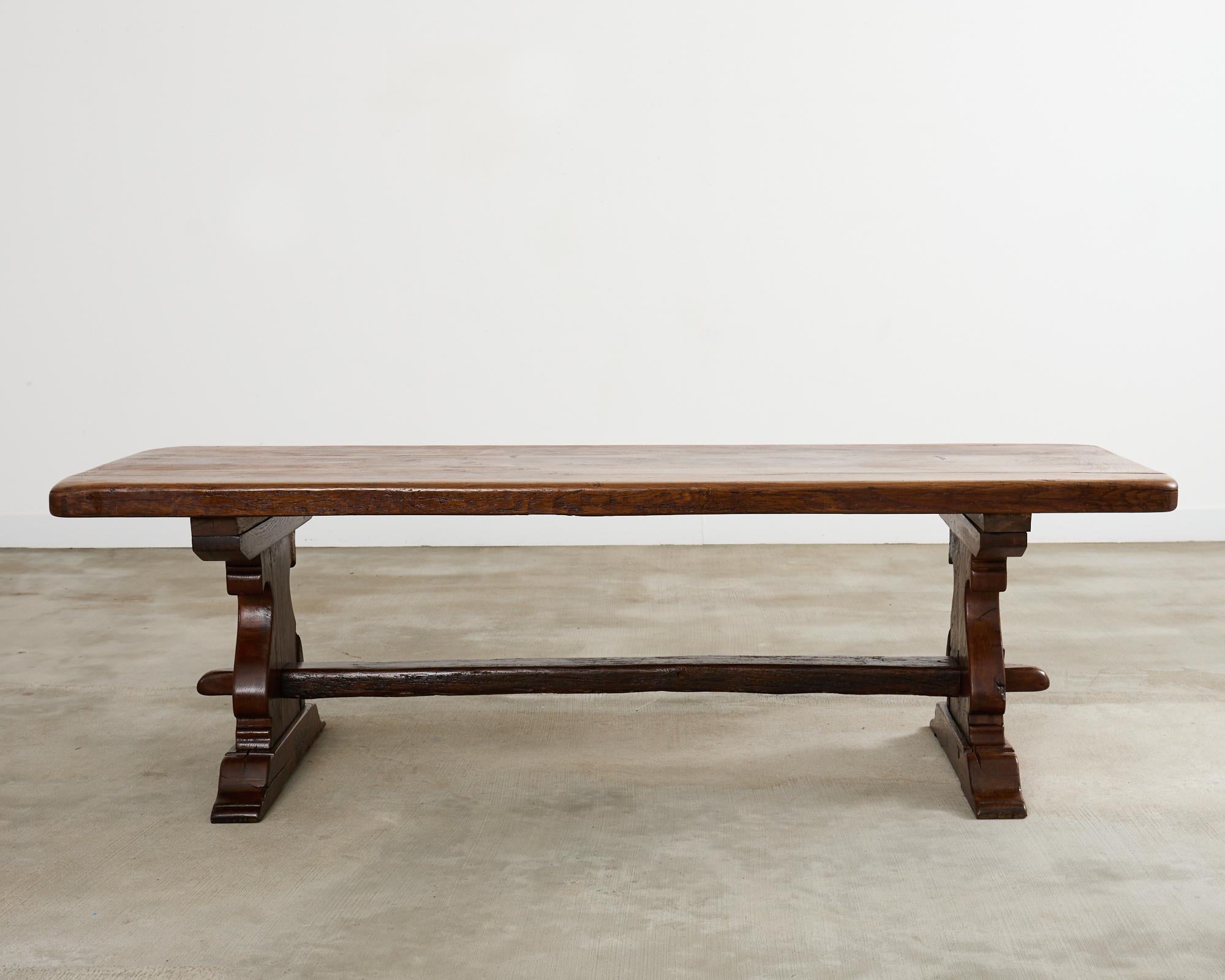 Mesa de comedor rústica provinciana francesa del siglo XIX fabricada con maderas macizas de roble. La mesa tiene un tablero macizo de casi 5 cm de grosor. La parte superior se apoya en patas en forma de pala unidas por un bastidor de carpintería de