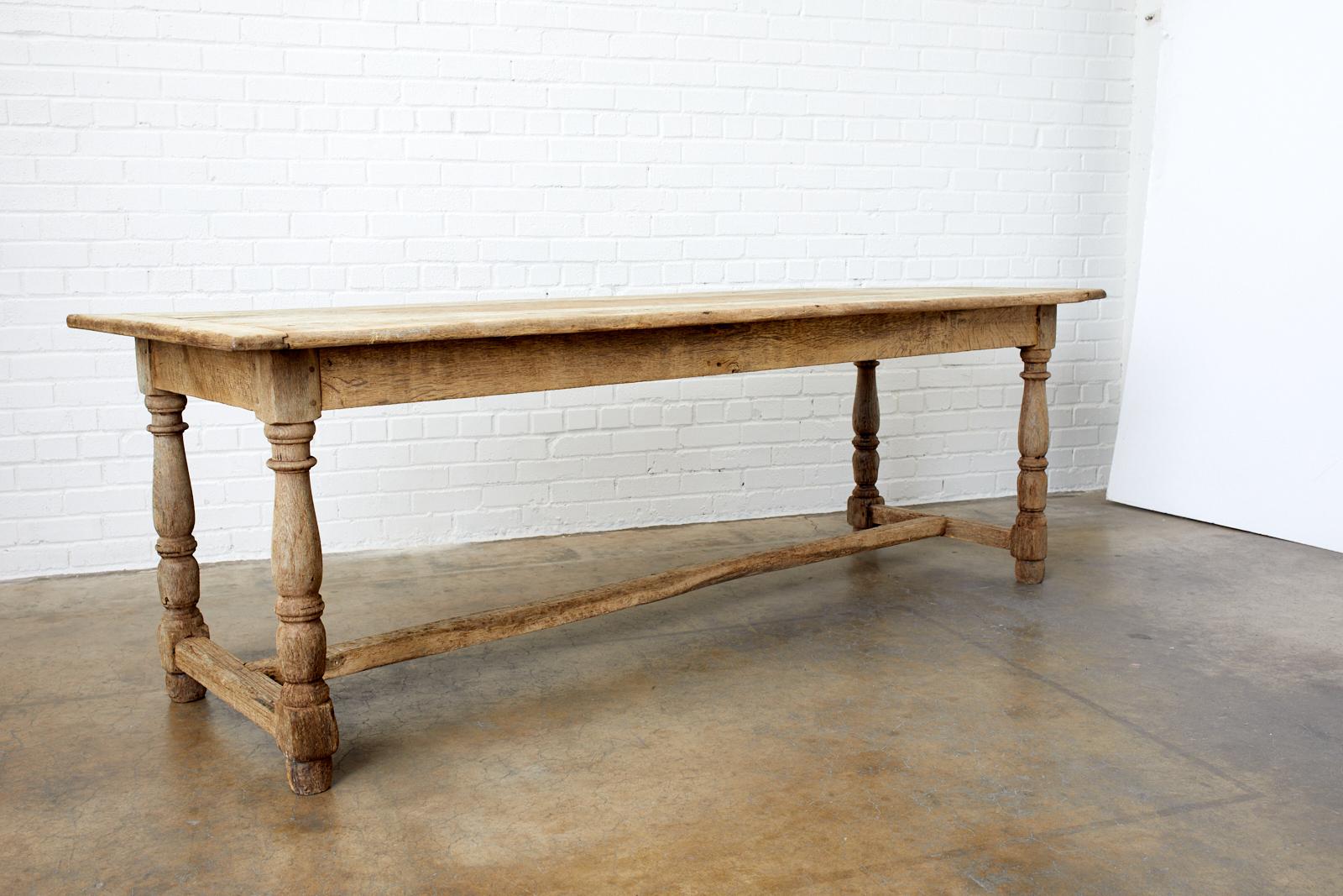 Spectacular 19th century country French farmhouse dining table featuring a bleached oak distressed finish. Made in a trestle style with a plank top and turned legs. Excellent peg joinery and craftsmanship with an aged patina on the oak that
