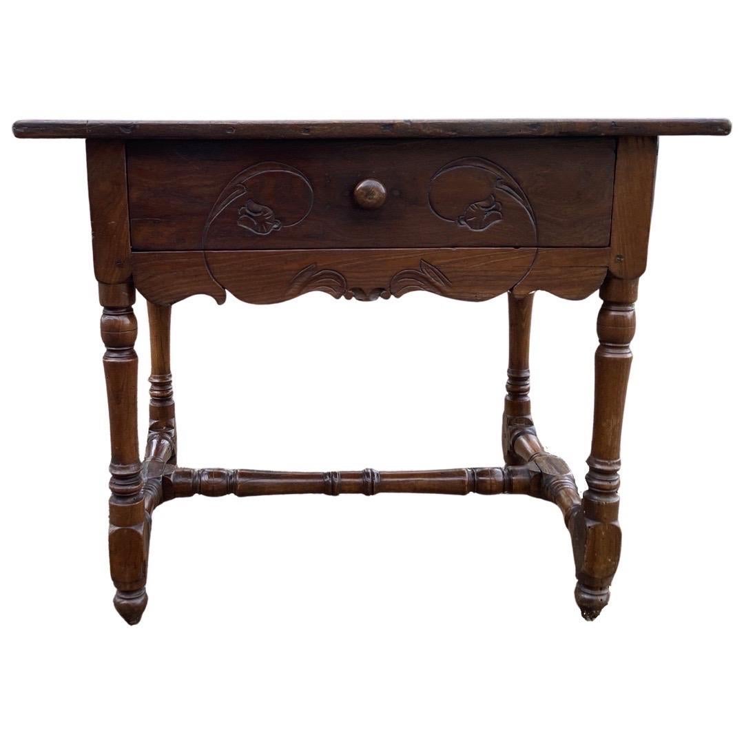 Oak side table hand-made in France in the early 1800s. This is a beautiful and delicate piece, built to be used and last. The top features three boards with straight edge nailed to a hand-carved apron. The apron shows tulips carved on three sides,