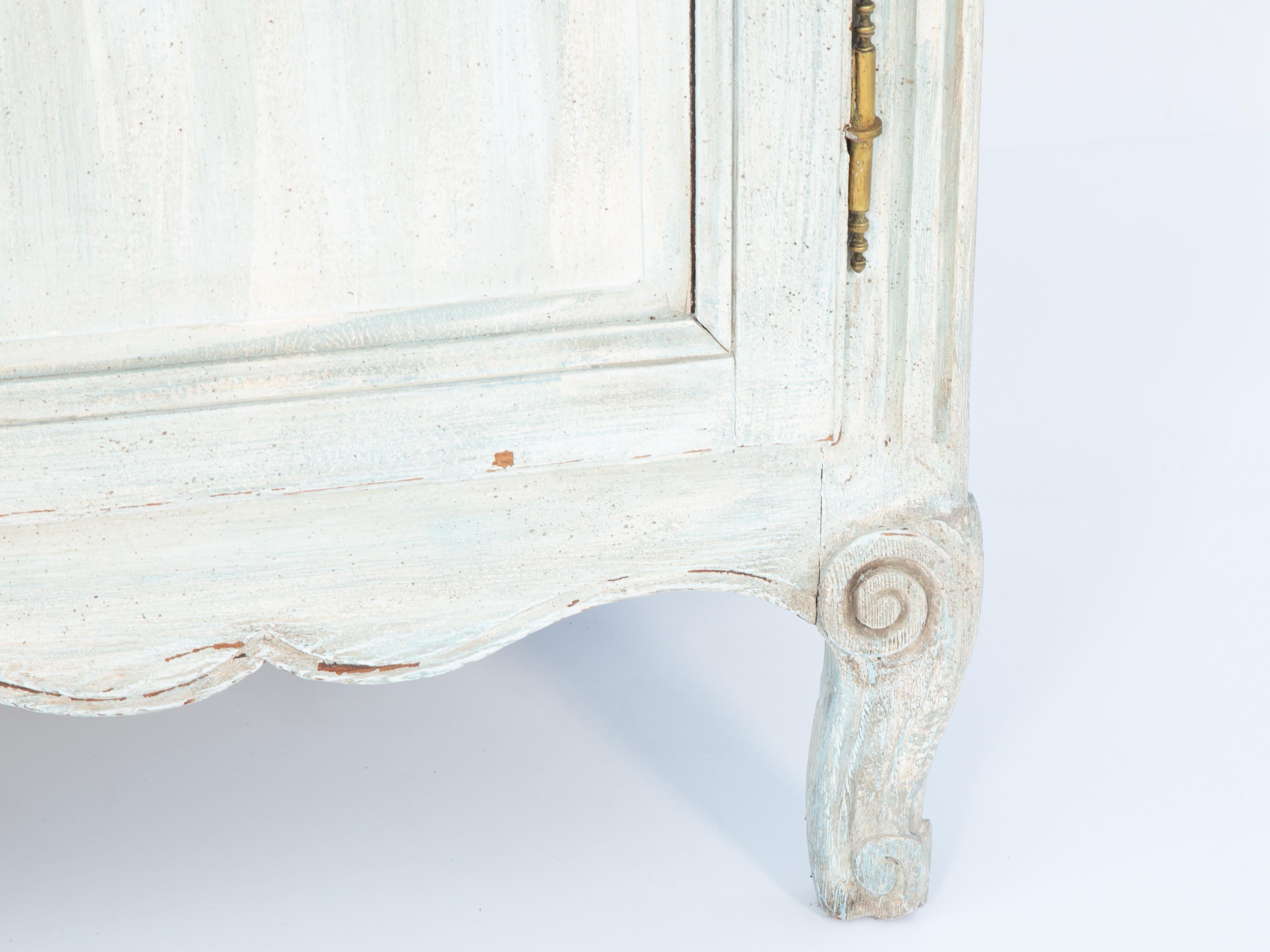 Louis XV style Provincial enfillade of painted walnut, having a molded rectangular top, over raised and fielded double cupboard doors, with hand-carved foliate and flora decoration and brass pierced escutcheons, opening to reveal two drawers and