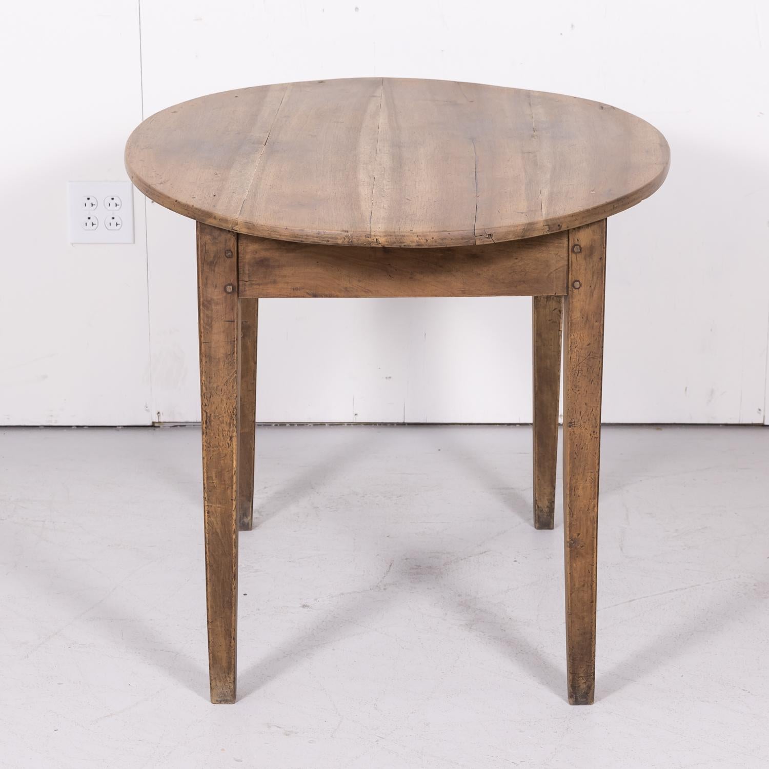 19th century Country French oval side table handcrafted in Lyon of solid walnut that has been bleached or washed to a natural finish and hand waxed to a beautiful patina, circa 1870s. Having an oval plank top over a single divided drawer, this