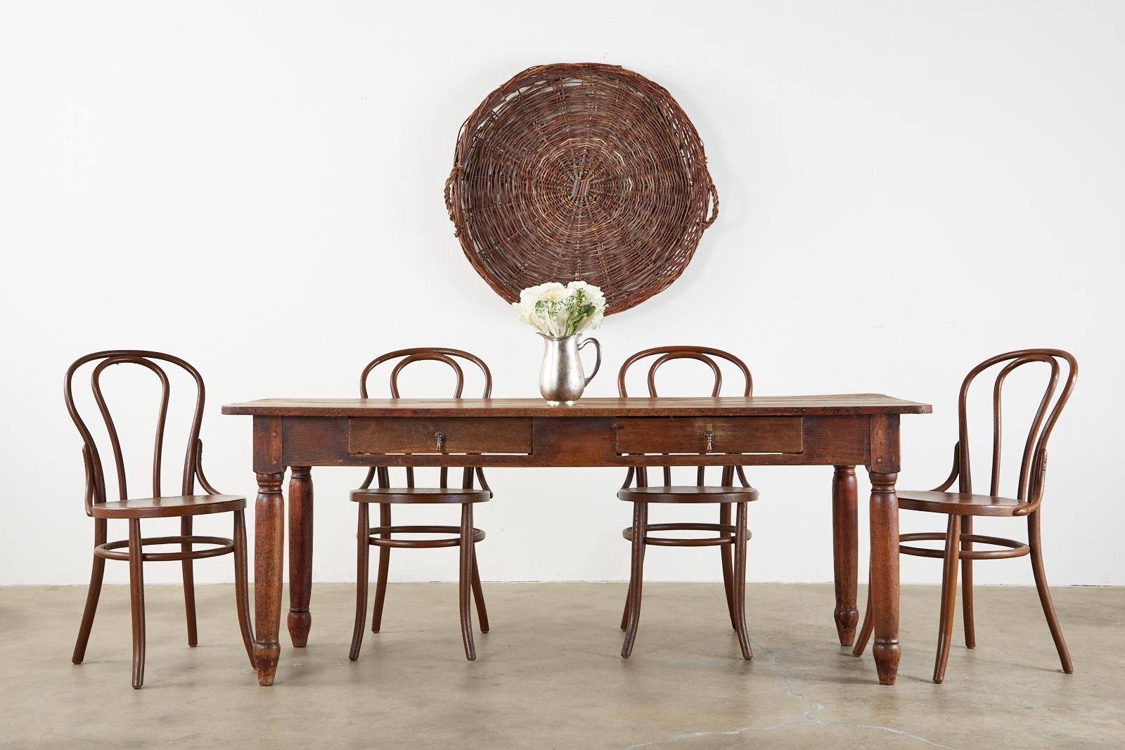 Rustic 19th century French provincial farmhouse dining table. Constructed from beautifully grained fruitwood with an aged patina and insect damage that adds to its character and charm. The frieze has two storage drawers with metal pulls. The table