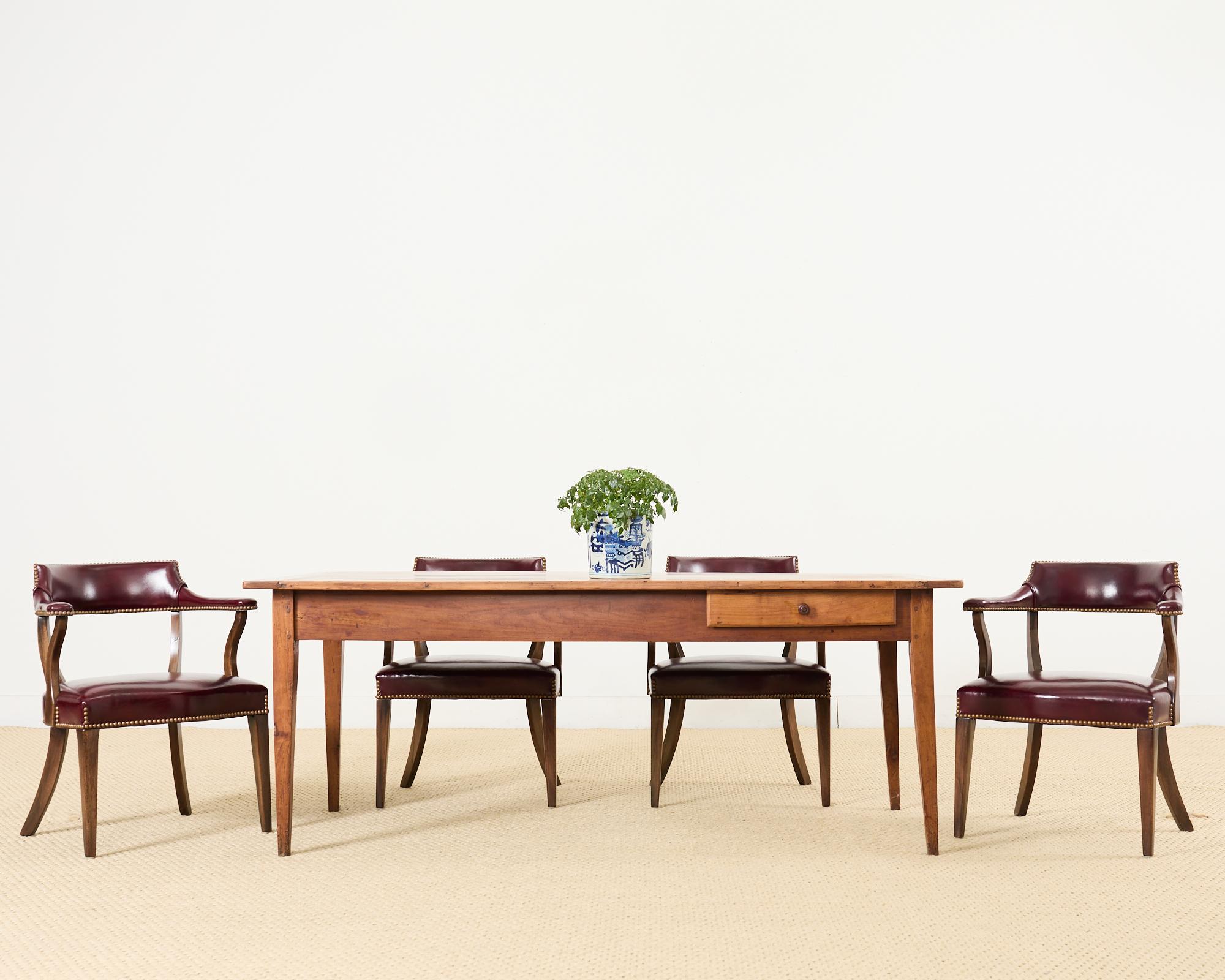 Gorgeous 19th century country French provincial farmhouse dining table crafted from fruitwood. The table features a thick plank top with bread board ends. Constructed with wood peg joinery and thick fruitwood with a warm honey toned finish. The