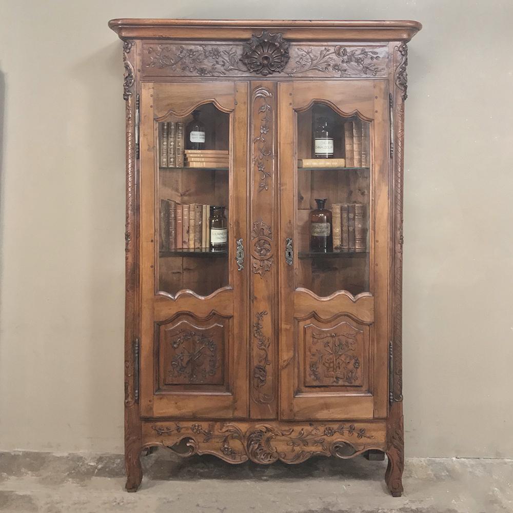 19th century Country French Provincial fruitwood vitrine ~ bookcase is a delightful example of aged fruitwood and rural artisanry displaying wonderful floral and foliate motifs from crown to base, with generous glazed doors ideal for showing off