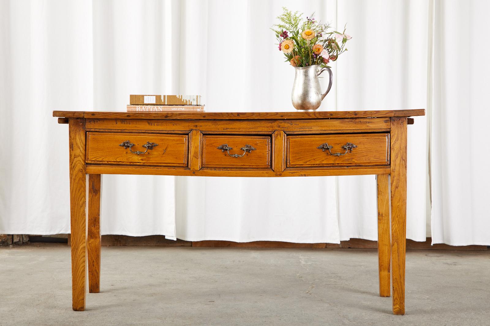 Distinctive 19th century country French Provincial console table crafted from pine. Originally a kitchen work table or server having pull-out cutting boards on each side. The thick plank top has breadboard ends. The case is fronted by three storage