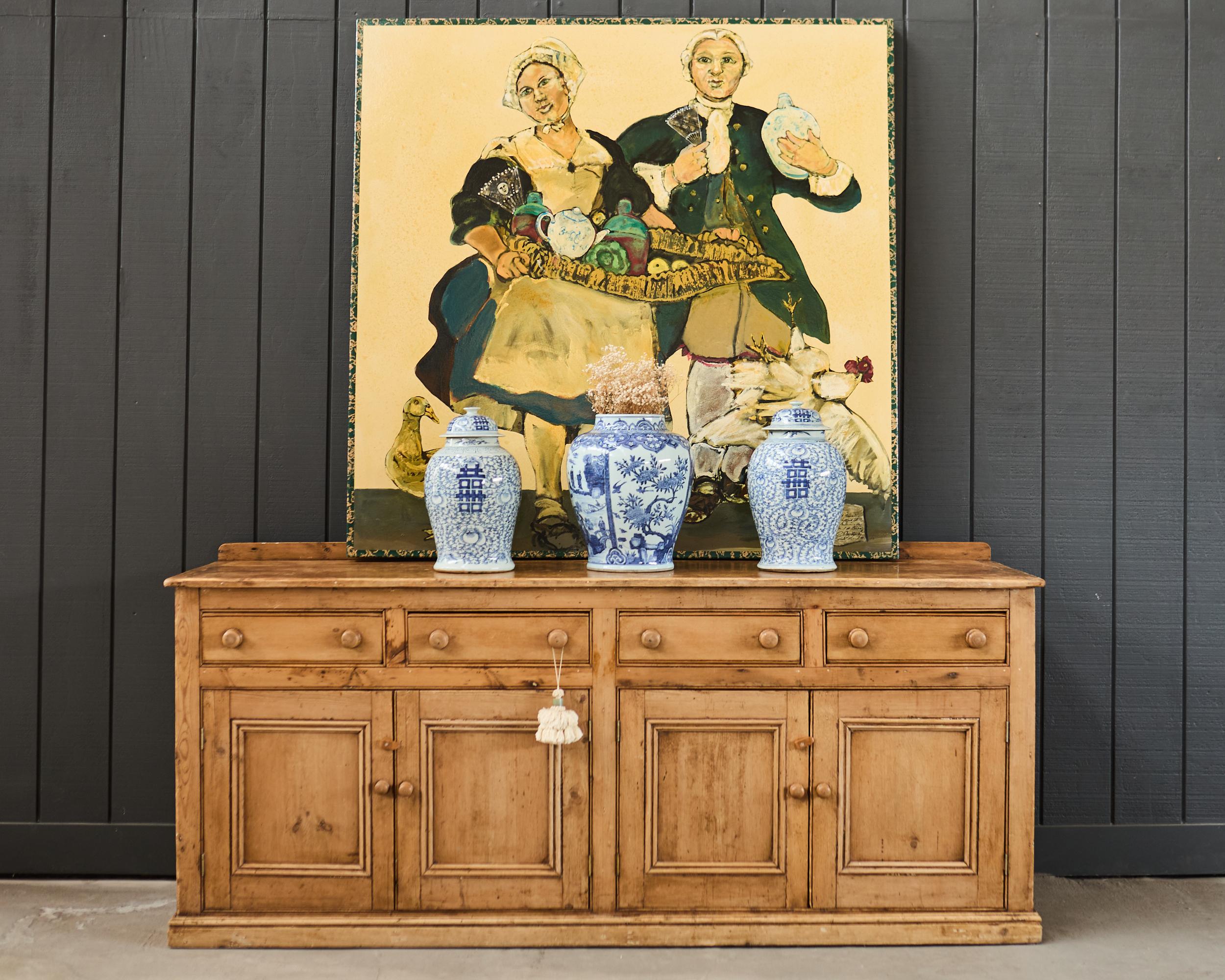 Weathered 19th century country French provincial sideboard, server, buffet, or dresser crafted from pine. The rustic cabinet has a thick top with breadboard ends and a small gallery in the back. The case is fronted by 4 storage drawers above 4 doors