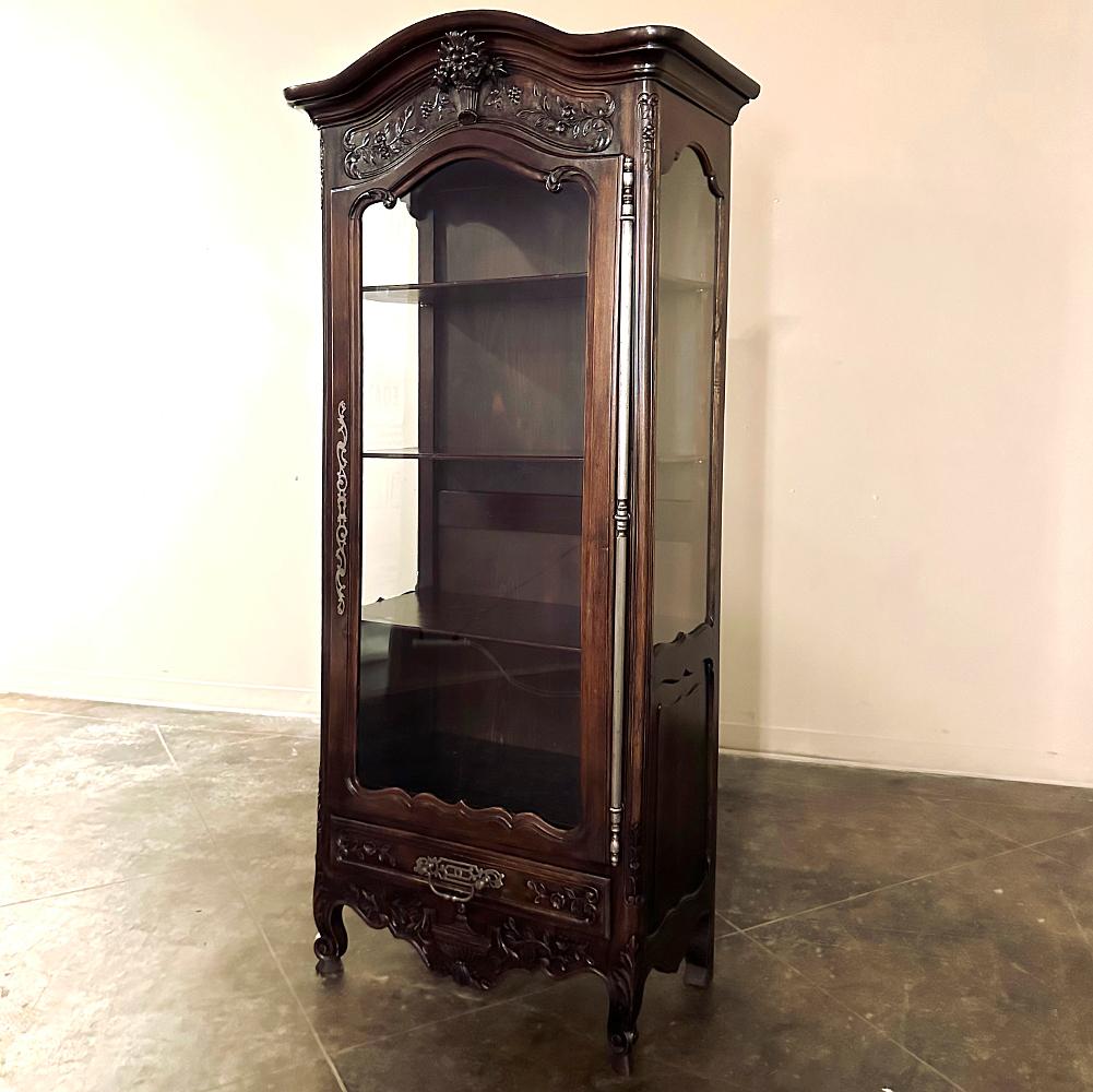19th century Country French Walnut Vitrine will make a stunning display case for your most prized possessions! Crafted in the inimitable French manner, it features a chapeau de gendarme crown over a bonnet lavished with a full relief basket of