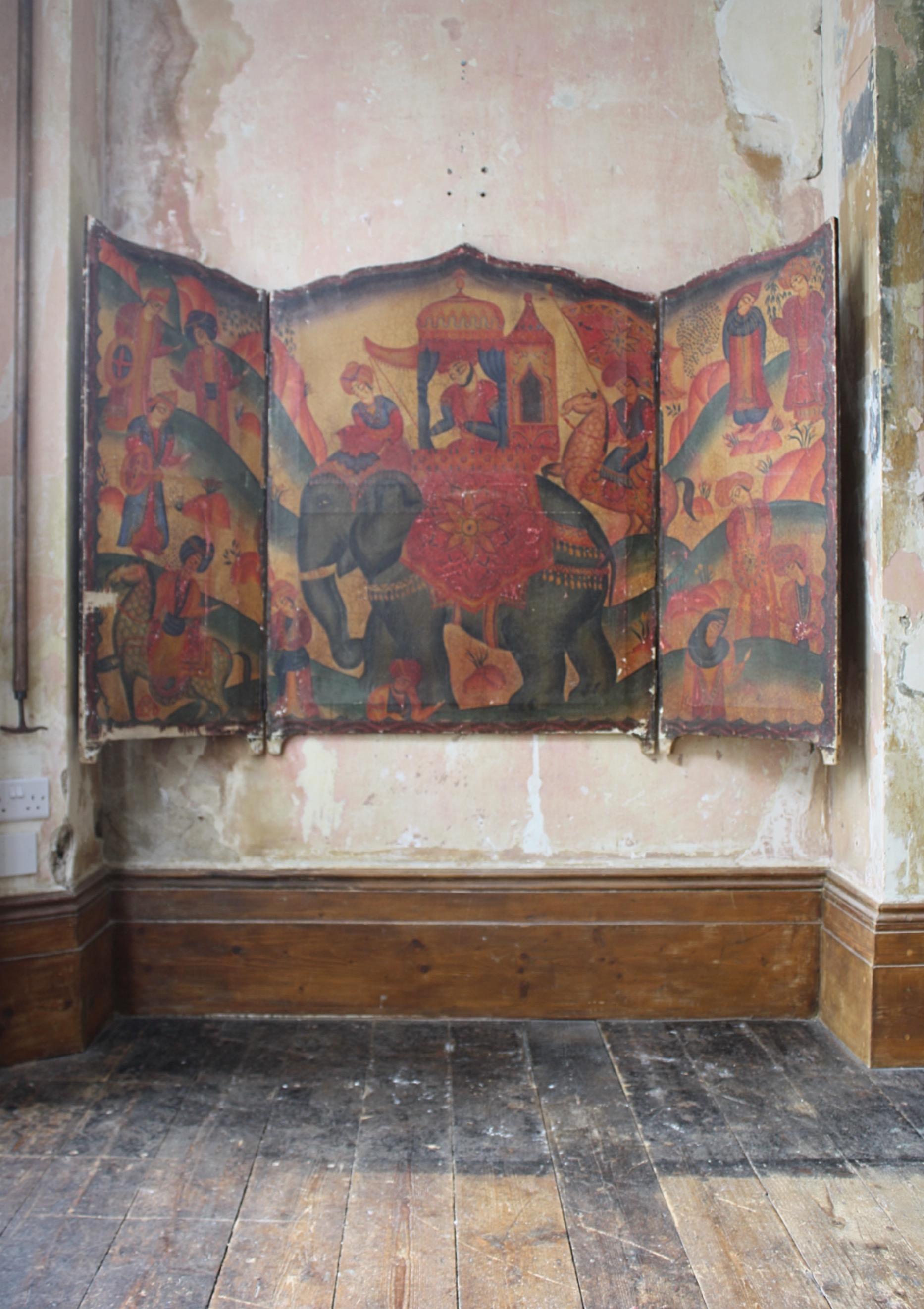 A painted 19th century Indian screen, depicting a charming scene with a man riding in a howdah on an elephant amongst other figures on horseback and standing amongst hills.

Painted on canvas stretched over a pine ogee formed frame, with areas of