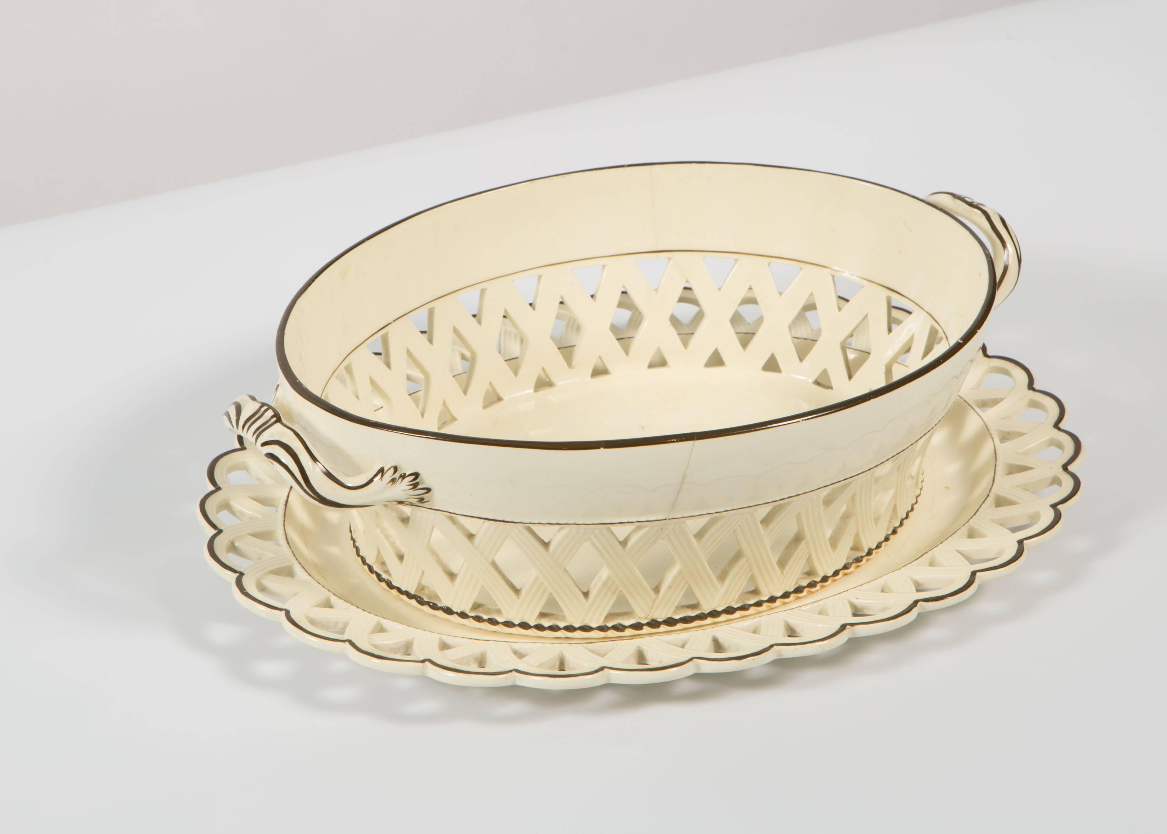 This is a 19th century cream ware bowl with brown accents on the bowl and the under plate. The bowl has a lattice design below the rim. The under plate has scalloped edging.