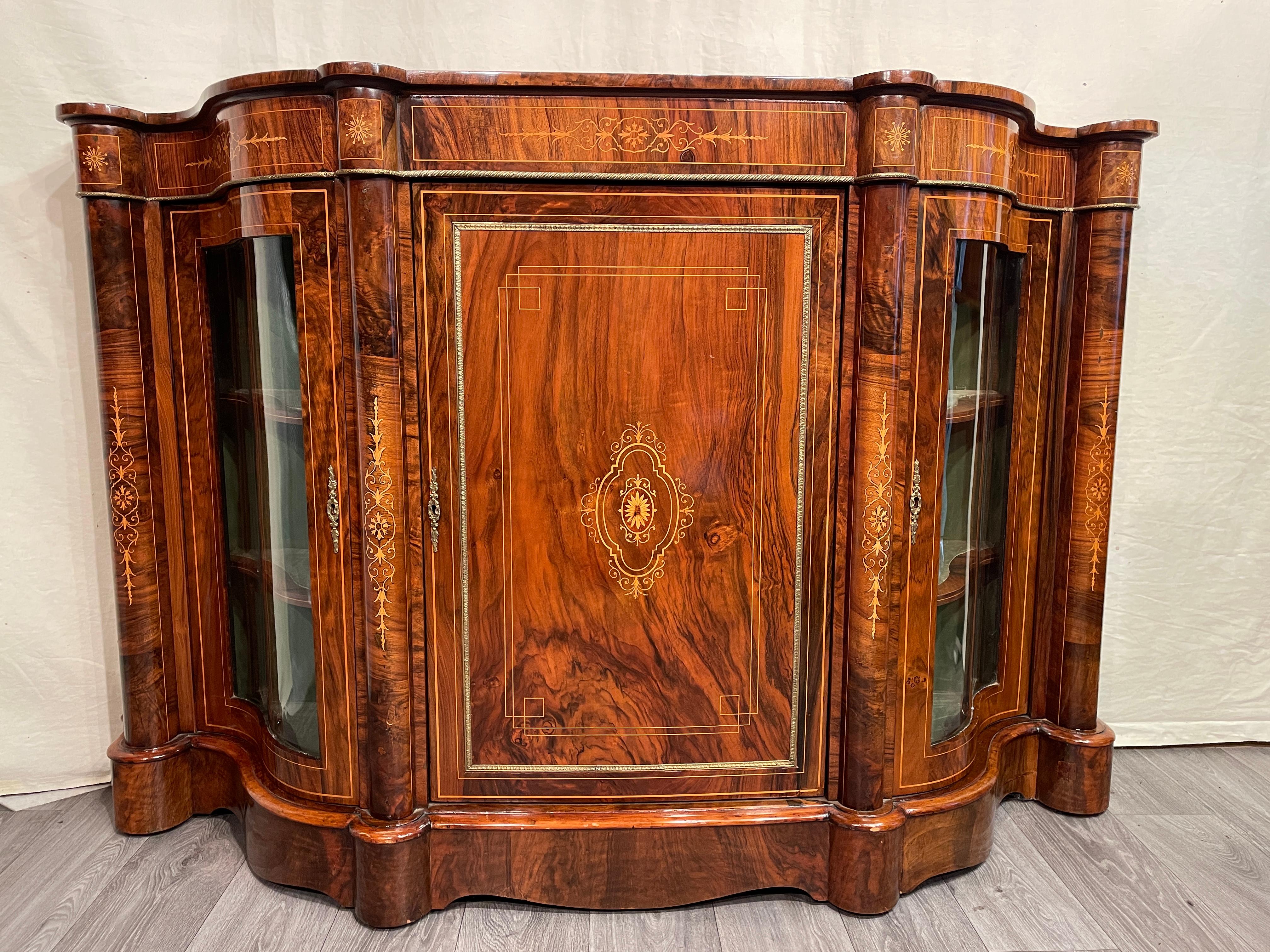 This gorgeous French Credenza was made during the 19th century. It is decorated with walnut veneer and has additional satinwood inlays of flower twines. The curved front is accentuated by four columns which are also decorated with twine inlays.