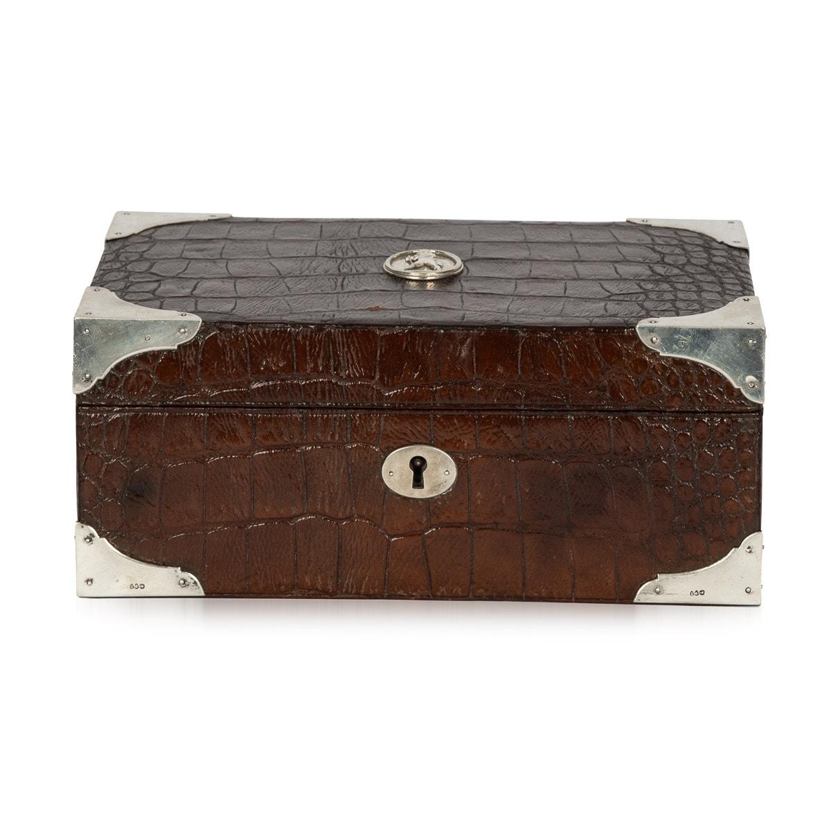 Antique 19th Century crocodile leather cigar humidor. This box features a solid silver cartouche of a top hat man on the centre top and solid silver corner protectors which wrap around the box. The inside is lined with cedar wood. The cigar box is