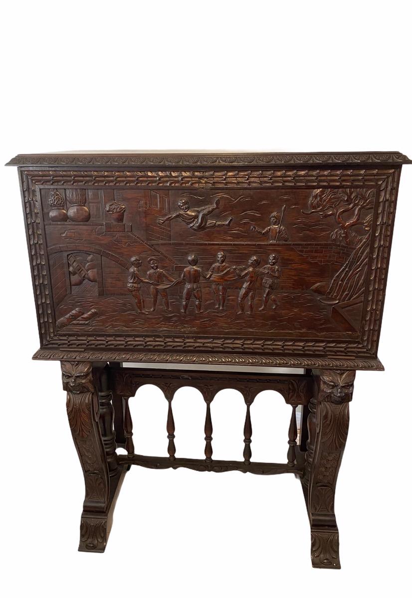 This Bargueno desk is hallmarked Garcia & HN Monte #122 Habana. It is embellished with a carving scene from the book of Don Quixote de la Mancha bordered with branches of leaves. The desk is supported by a pedestal joined by a bridge of turned