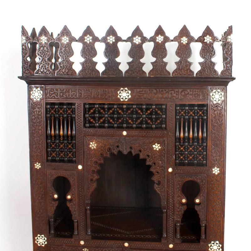 Cupboard or cabinet with an intricately carved case, Moorish arches, stick and ball breathers and columns all with mother of pearl inlays. Storage behind two doors and open display for your treasures.