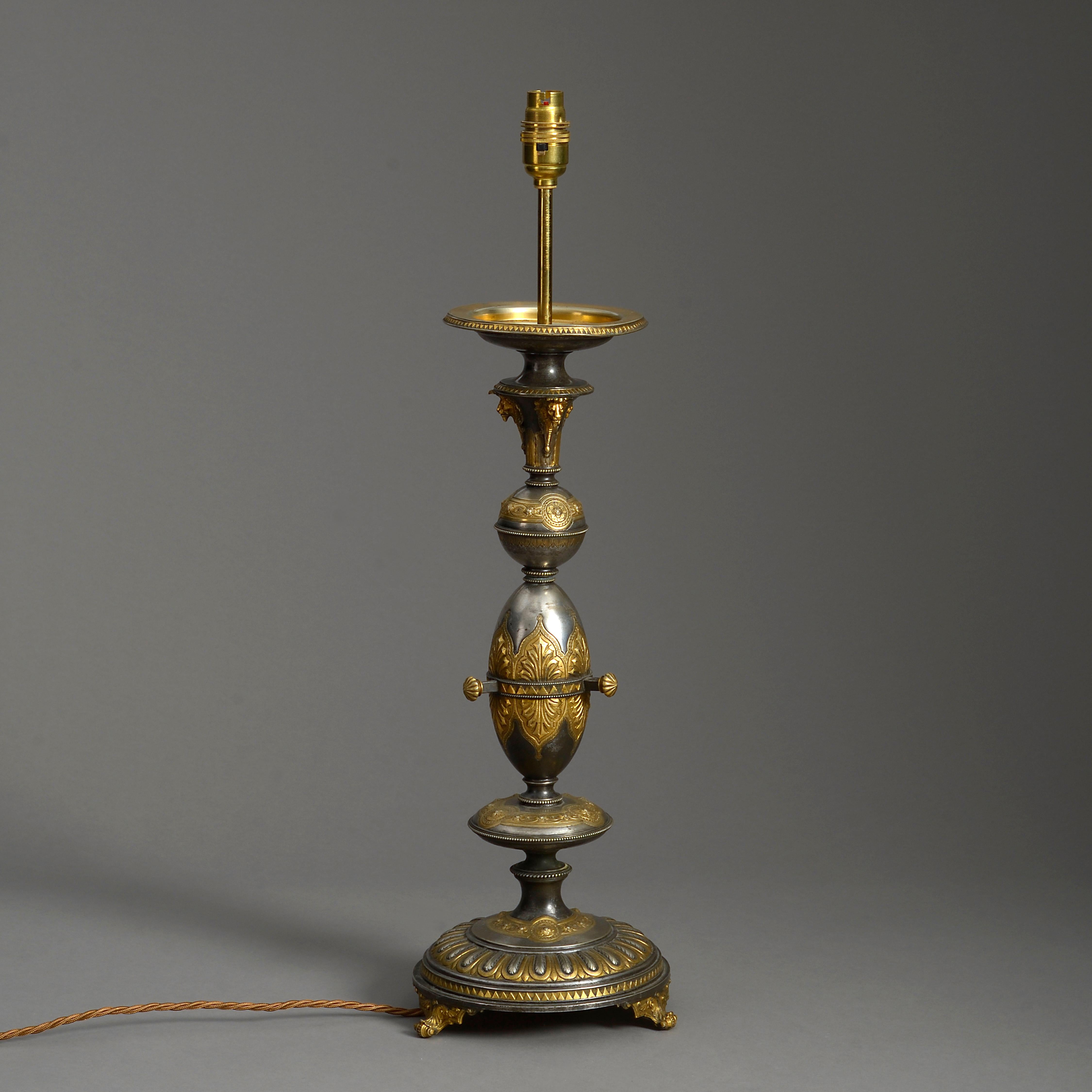 A nineteenth century cut steel and gilded steel column lamp, decorated with stylised lion masks, palmettes, beading and gadrooning.

The top stamped with registration mark.

Height refers to antique elements (not including electrical