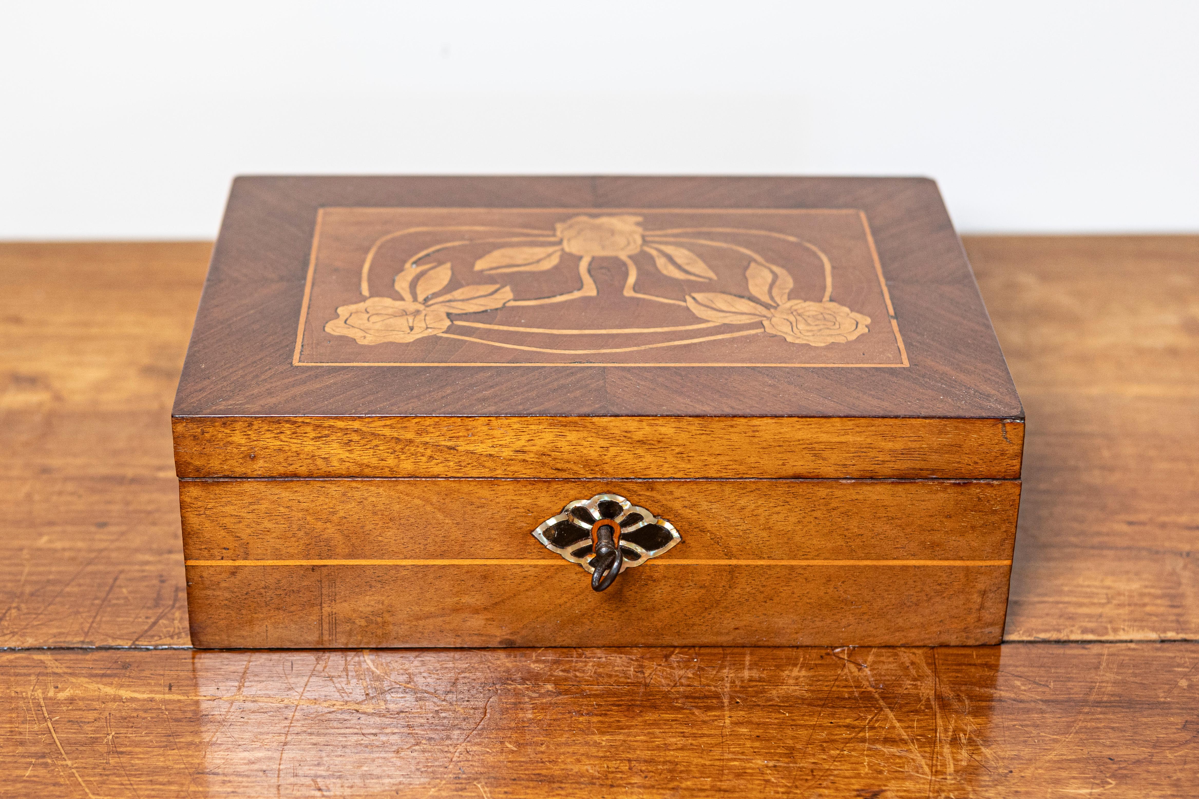 Questa squisita scatola danese del XIX secolo, risalente al 1880 circa, mette in mostra l'eleganza e la maestria dell'epoca. Realizzata in caldo legno di noce, la scatola presenta un motivo floreale finemente intarsiato sul coperchio, reso con