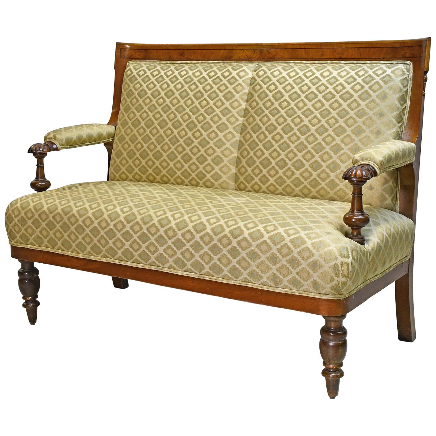 A small and comfortable canapé or settee in figured walnut with ebonized inlaid banding. Legs are turned out of beechwood and stained. Offers upholstered arm rests, back and seat, with eight-way, hand-tied springs that have been pulled tight &