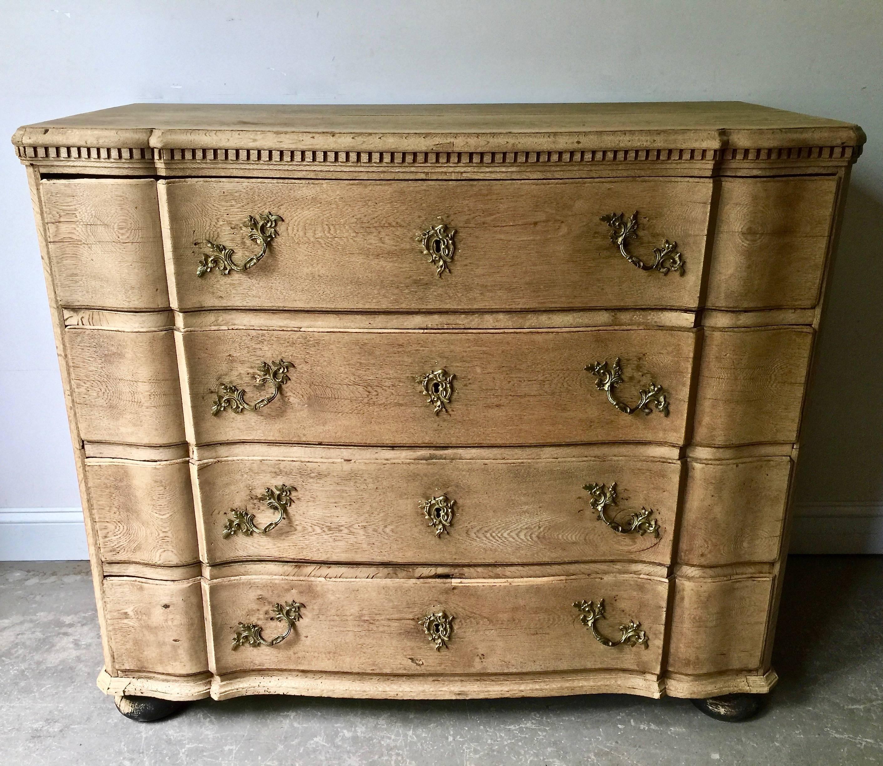 19th century chest of drawers in richly carved bleached oak with curvaceous serpentine drawer fronts, handsome bronze hardwares and shaped top with dental decorations. The chest is in two parts with original large handsome handles for convent