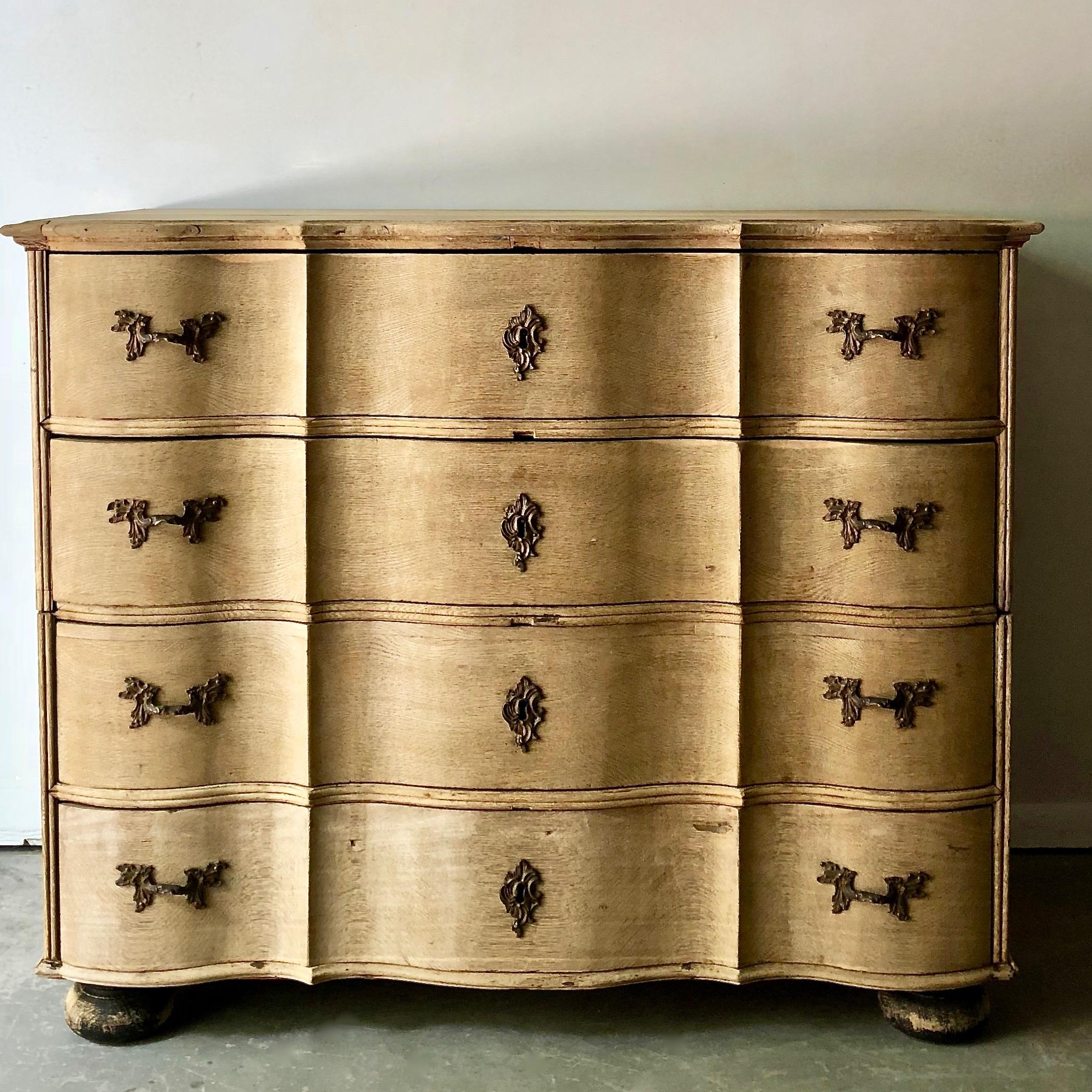 19th century chest of drawers in richly carved bleached oak with curvaceous serpentine drawer fronts, handsome bronze hardwares and shaped top and ball feet. The chest is in two parts for convent travels. 
Denmark, circa 1850. 
More than ever, we