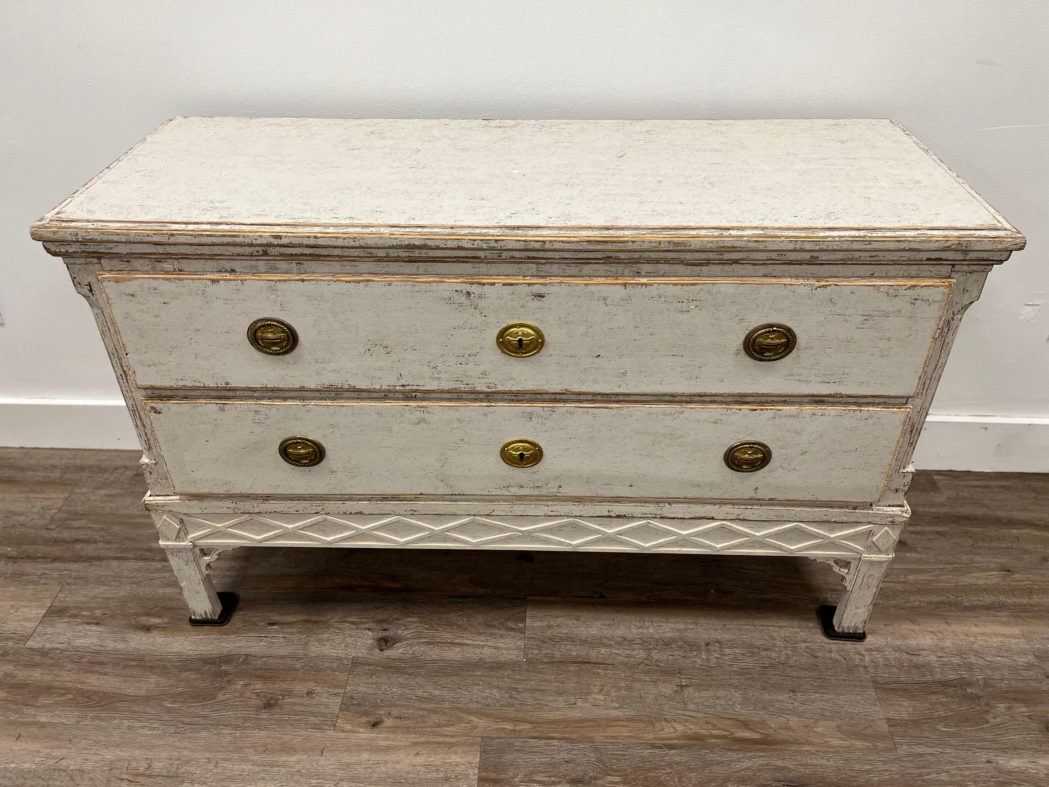 A Danish Late Gustavian commode with old (possibly original) brass hardware and locks. Notched corners with two wide drawers over a crisscross patterned apron. Square legs with small, decorative apron supports. Tastefully repainted in soft grey. 