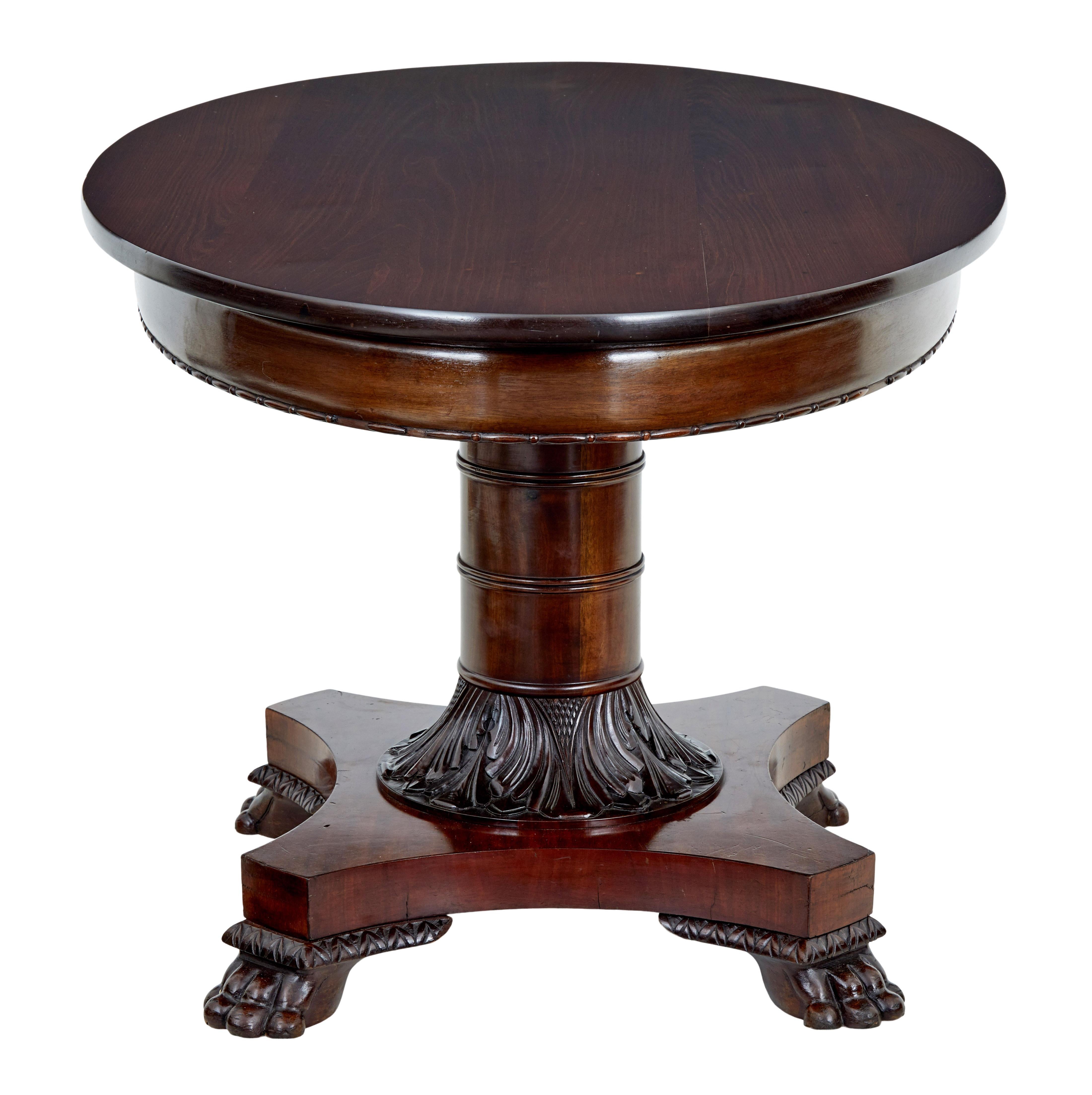 Fine quality oval mahogany center table, circa 1860.

Solid mahogany top with applied carved detail to the frieze. Standing on a fantastic gun barrel stem base, carved collar links to the quadriform. Standing on carved paw feet.

Top surface has