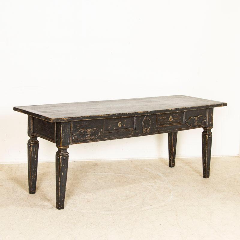 This attractive console table originally served as a narrow library table in Denmark. Note the attractive applied carving to the front, tapered legs and deep apron with two drawers. The table has been given a newer black, rubbed out finish fitting
