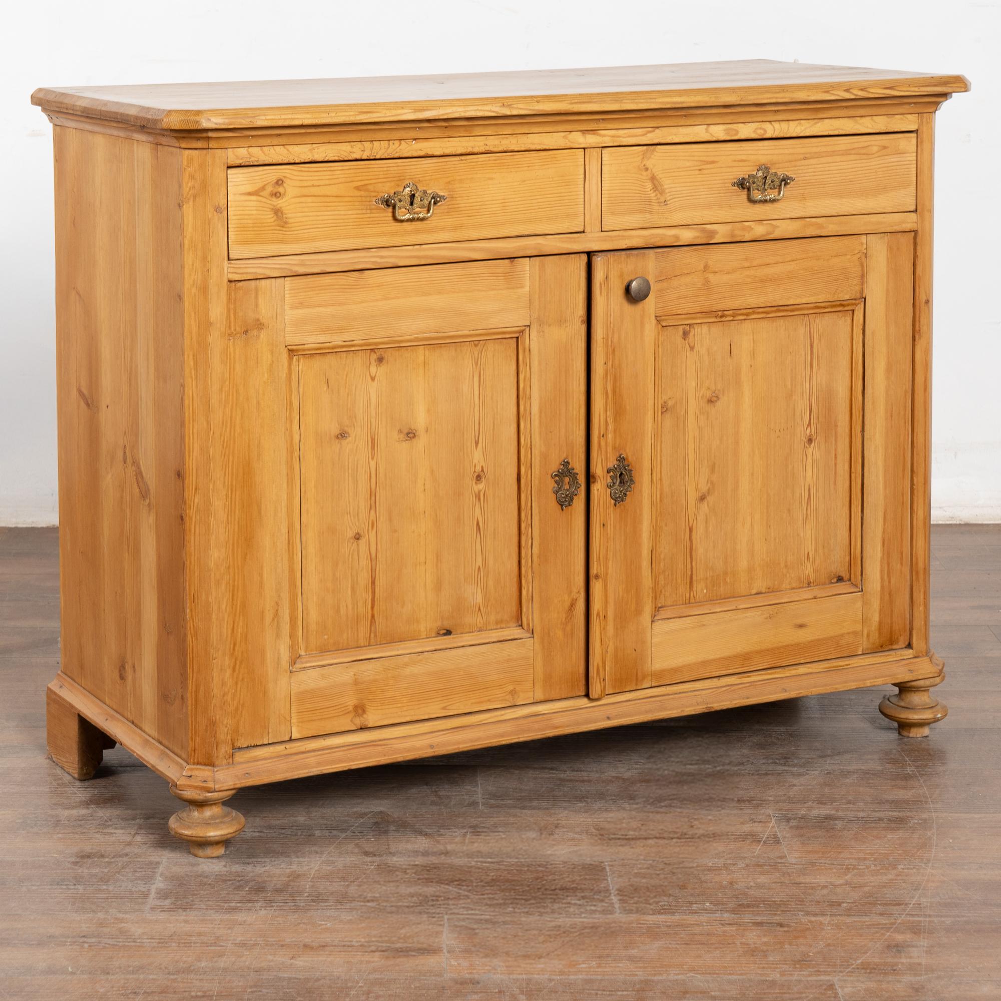 Credenza in pino danese dalle linee pulite; due cassetti su due ante, un ripiano interno.
Restaurato e cerato, questo mobile è stabile, robusto e pronto all'uso. I cassetti funzionanti sono dotati di tiretti in ottone. Nessuna serratura per le ante