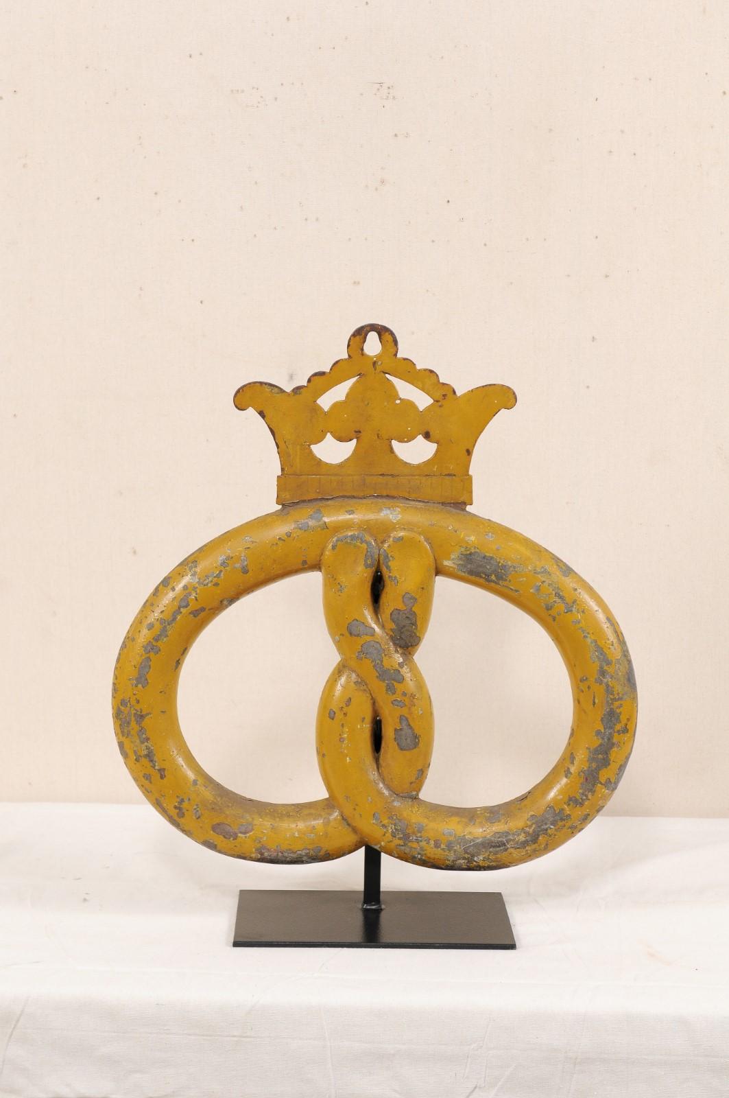 A 19th century baker's pretzel shop sign from Denmark, mounted on custom iron Stand. This antique pretzel, formed of metal, originally would have hung from an arm extended out near the exterior entrance of a bakery or pastry shop. The pretzel is