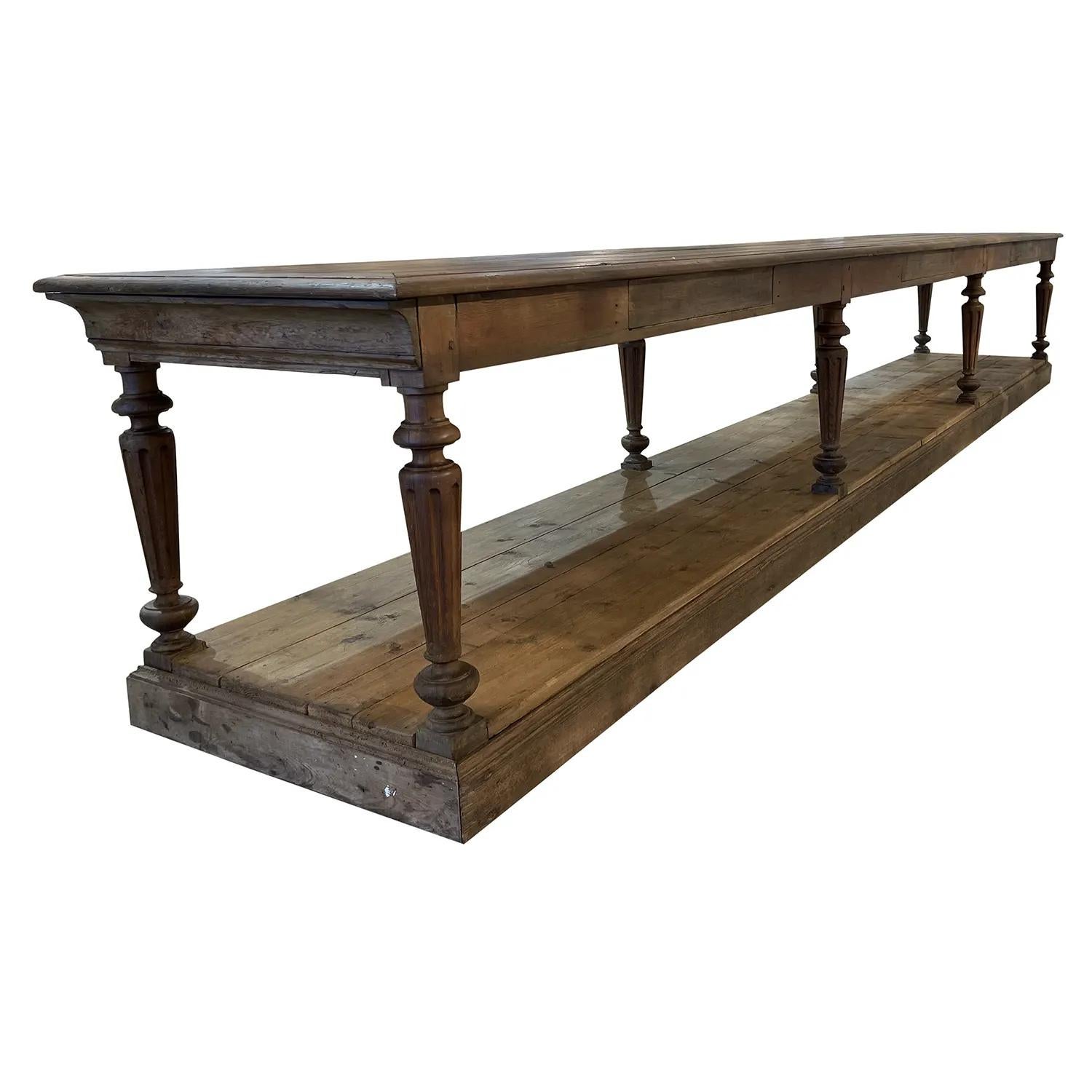 A 19th century, dark-brown antique monumental French tailor’s, drapers table made of hand crafted oakwood, in good condition. The large table is detailed with a scrubbed top, composed with a heavy low shelf, standing on eight round turned legs.