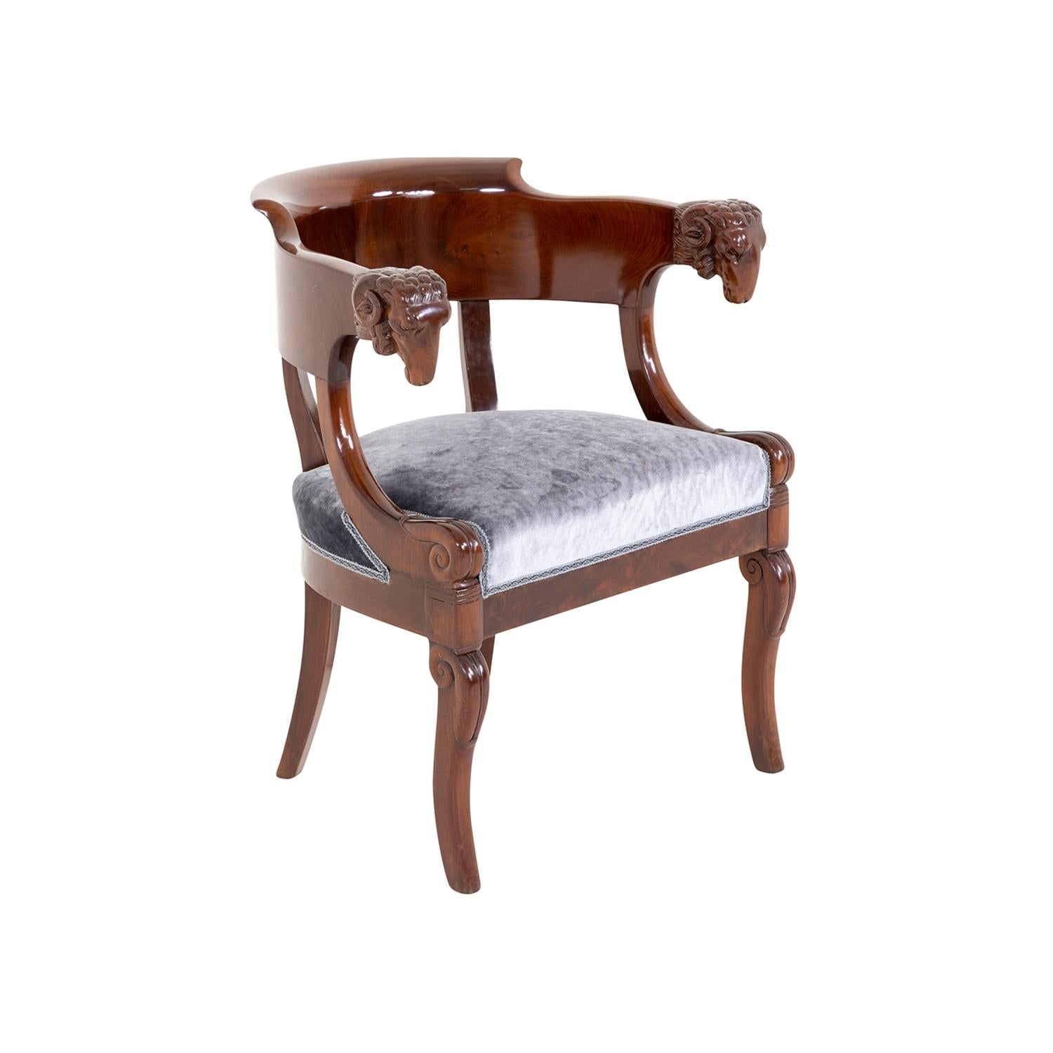 A dark-brown, antique German Biedermeier single armchair made of hand shellac polished Mahogany, in good condition. The detailed side chair has a half round, arched backrest with slim armrests which are particularized with rams heads. The corner